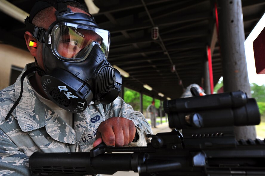 Senior Airman Micah Moody, 96th Civil Engineer Squadron firefighter, charges an M-4 Carbine rifle, April 9, 2015, at Hurlburt Field, Fla. Students are required to don gasmasks to simulate a chemical warfare environment during one aspect of qualifying on the M-4. (U.S. Air Force photo/Airman 1st Class Ryan Conroy)