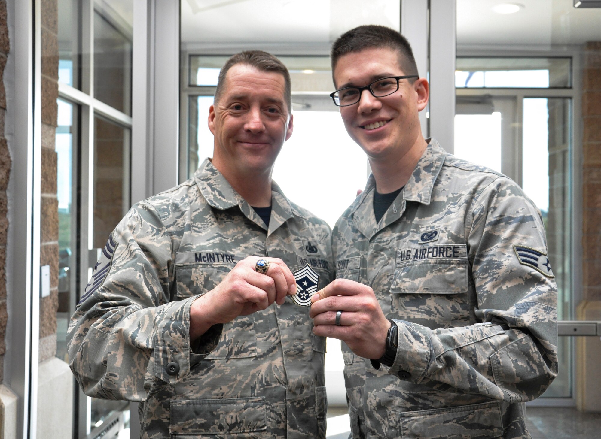 Chief Master Sgt. Douglas McIntyre, Air Force Space Command command chief, coins Senior Airman Darren Scott, 460th Space Wing Public Affairs, during his base visit April 9, 2015, on Buckley Air Force Base, Colo. During his visit, McIntyre spoke on Buckley AFB’s vast mission, its importance to national security, and the Airmen who accomplish the mission every day. (U.S. Air Force photo by Tech. Sgt. Nicholas Rau/Released)