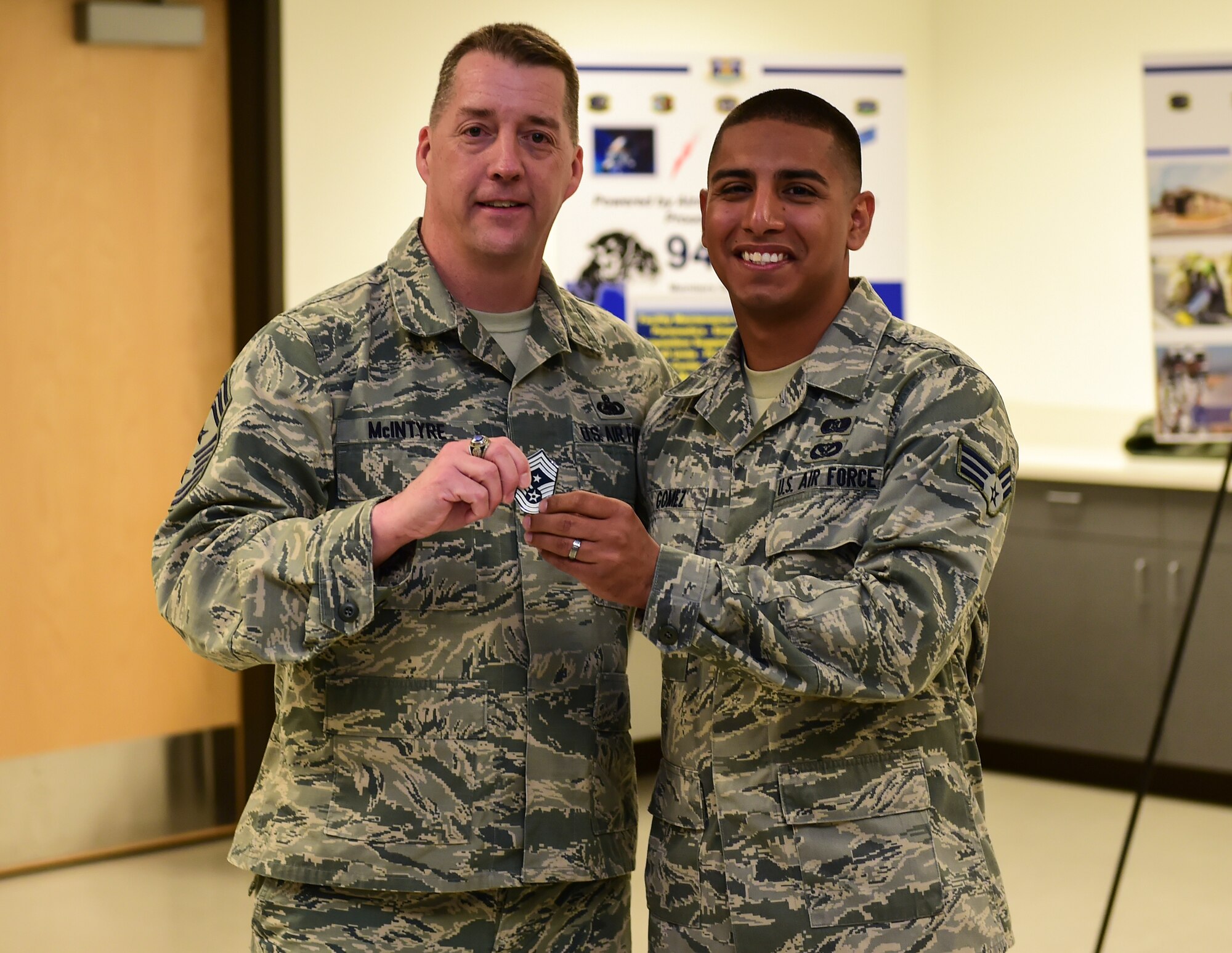 Chief Master Sgt. Douglas McIntyre, Air Force Space Command command chief, coins Senior Airman Carlos Gomez, 460th Civil Engineer Squadron, during his base visit April 9, 2015, on Buckley Air Force Base, Colo. During his visit, McIntyre spoke on Buckley AFB’s vast mission, its importance to national security, and the Airmen who accomplish the mission every day. (U.S. Air Force photo by Airman 1st Class Luke W. Nowakowski/Released)