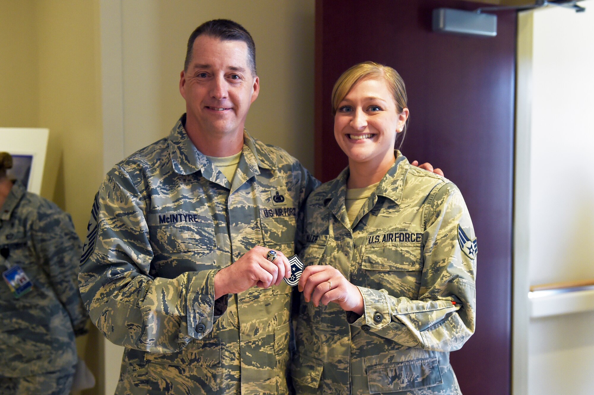 Chief Master Sgt. Douglas McIntyre, Air Force Space Command command chief, coins Senior Airman Christina Miller, 460th Medical Group, during his base visit April 9, 2015, on Buckley Air Force Base, Colo. During his visit, McIntyre spoke on Buckley AFB’s vast mission, its importance to national security, and the Airmen who accomplish the mission every day. (U.S. Air Force photo by Airman 1st Class Emily E. Amyotte/Released)