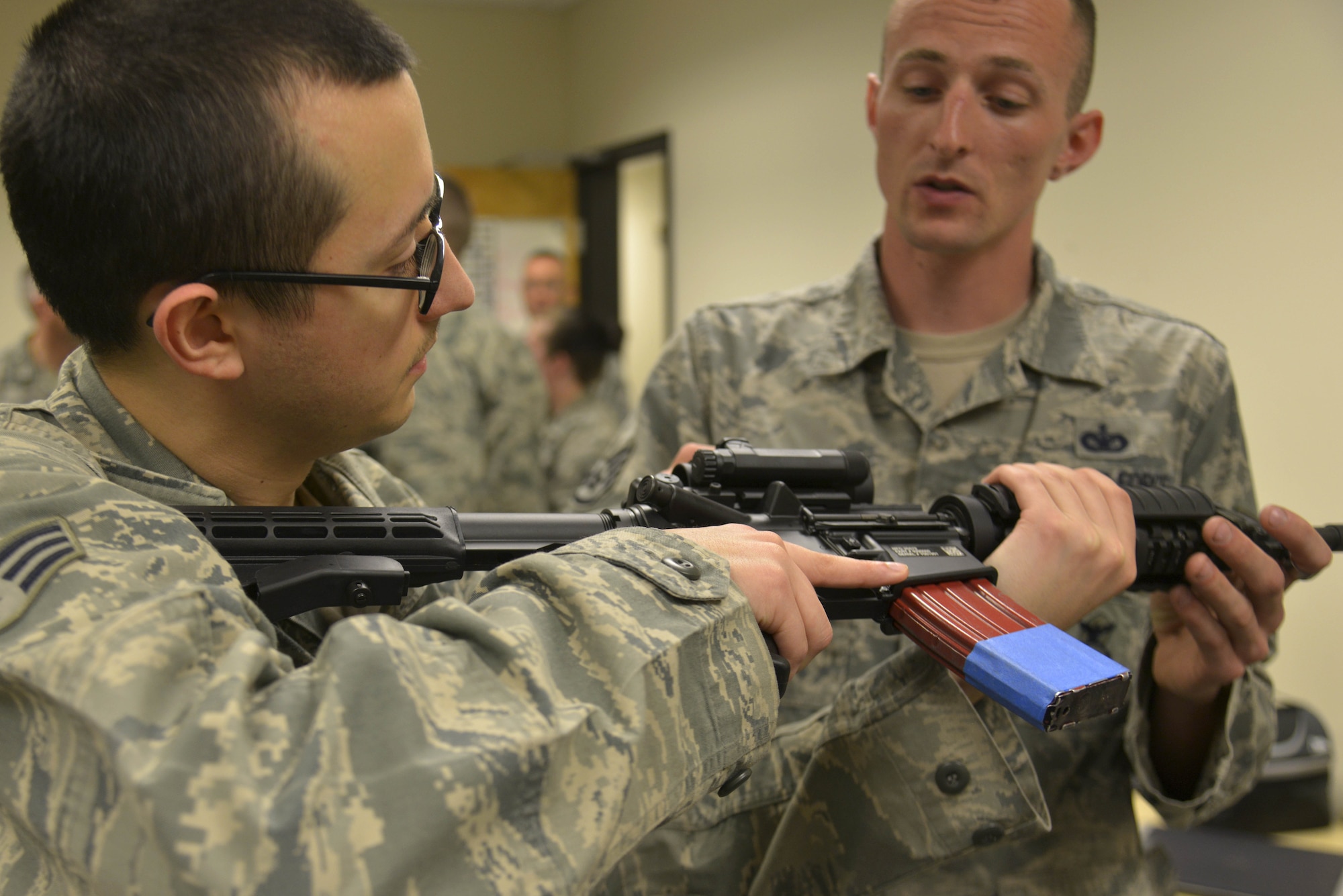 Staff Sgt. Troy Tulleners, 92nd Security Forces Squadron combat arms instructor, teaches Senior Airman Robert Curtis, 92nd Communications Squadron cyber transport technician, procedures on how to clear an M4 Carbine Assault Rifle during Operation M4 April 6, 2015, at Fairchild Air Force Base, Wash. Chief Master Sgt. Christian Pugh, 92nd Air Refueling Wing command chief, went around the communications squadron building testing Airmen's knowledge on how to use the weapon. (U.S. Air Force photo/Senior Airman Janelle Patiño)