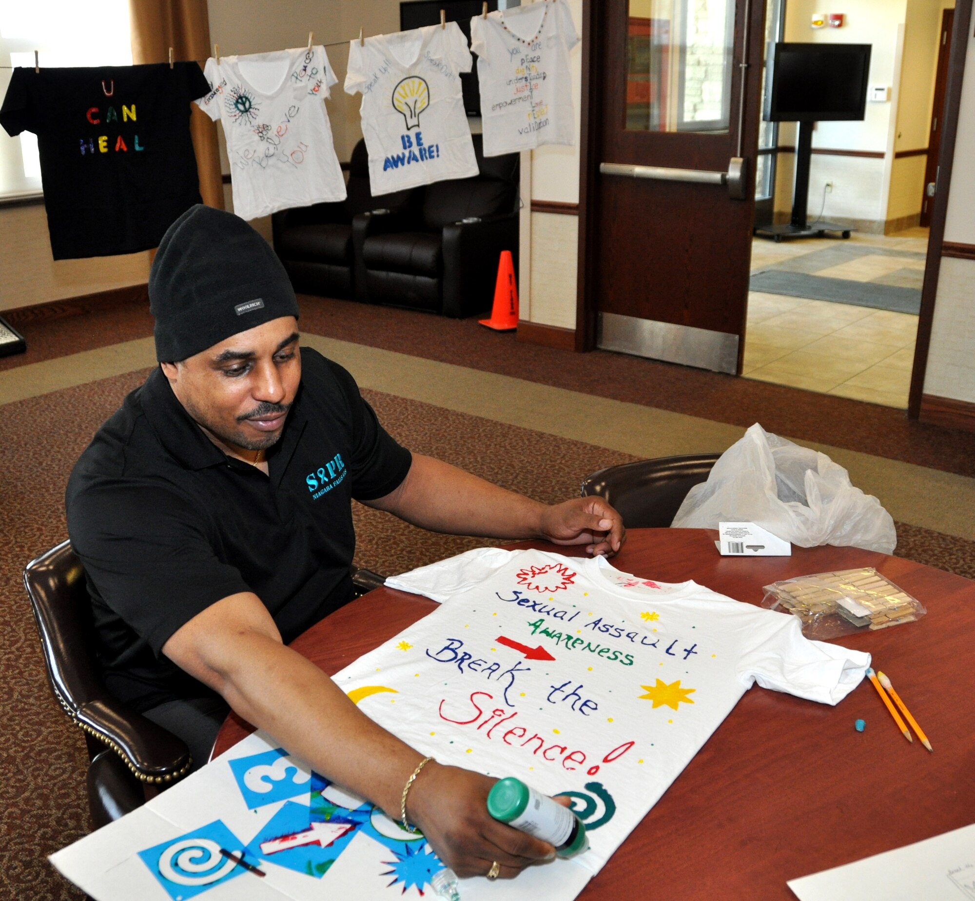 Murray Taylor, 914th Airlift Wing Contracting Specialist, puts the finishing touches on a T-shirt he created as part of the Clothesline Project at the Niagara Falls Air Reserve Station, N.Y. April 6, 2015.  April is Sexual Assault Awareness Month and this project, one of several at the base, uses the concept of hanging shirts on a clothesline as a vehicle for raising awareness about the issue of personal violence. (U.S. Air Force photo by Master Sgt. Kevin Nichols)