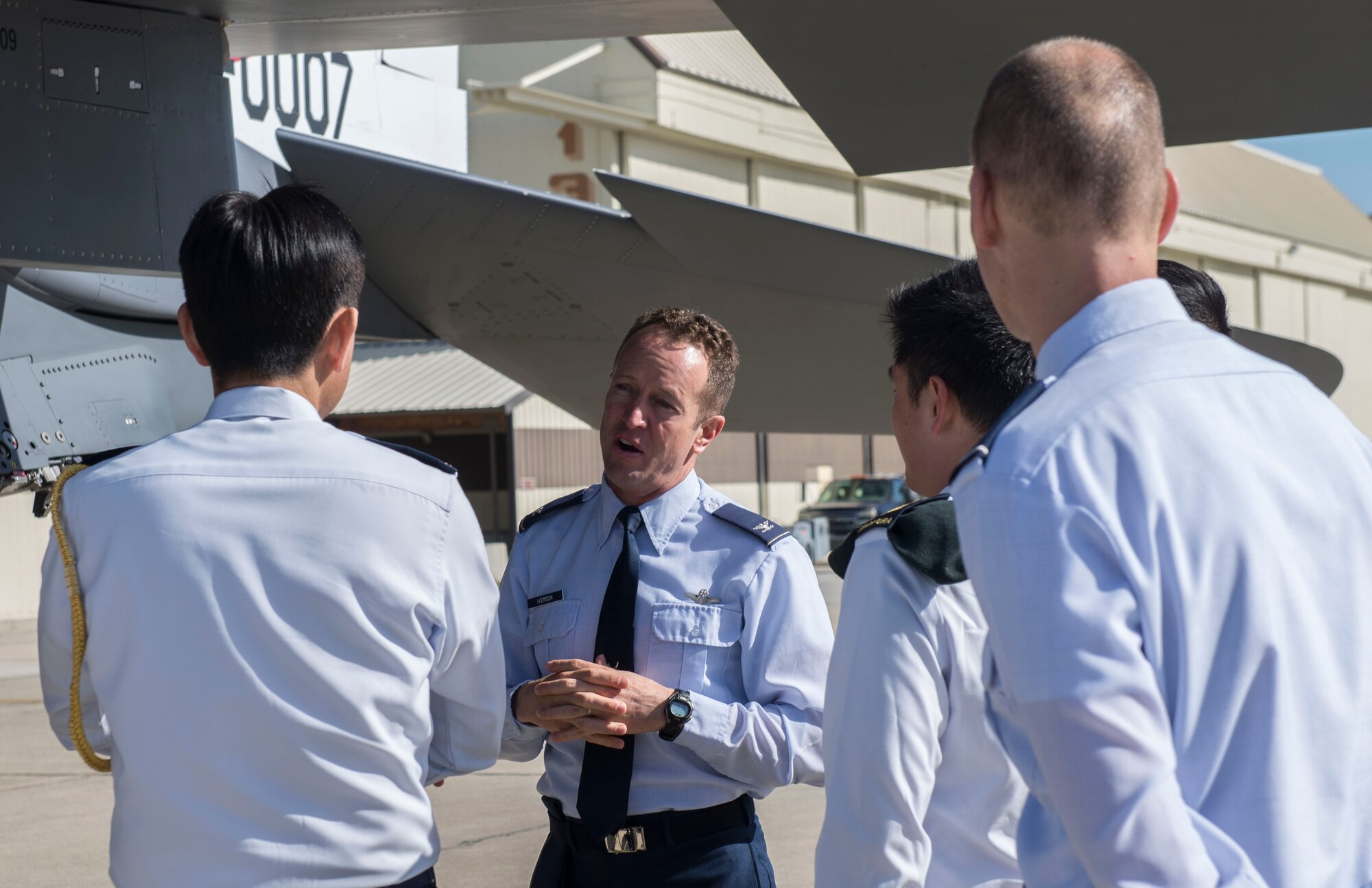 366th Fighter Wing commander, Col. David Iverson, talks with Singapore defense attaché, Brig. Gen. Leong Kum Wah and other service members at Mountain Home Air Force Base, Idaho, April 9, 2015. Iverson and Wah were able to discuss the different aspects that go into making aircraft work. (U.S. Air Force photo by Airman 1st Class Jessica H. Smith/RELEASED)