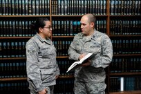 Capt. Eliot Peace, 502nd Security Forces and Logistics Support Group assistant staff judge advocate,  (right) and Senior Airman Maria Fernanda Cortez-Garcia, 502nd Security Forces and Logistics Support Group  legal office paralegal,  take a closer look at provisions for the Uniformed Code of Military Justice at Joint Base San Antonio-Randolph. (U.S. Air Force photo by Harold China/Released)