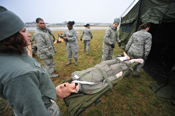 Airman 1st Class Jennifer Jackson and Airman Destinee Capponi, 166th Medical Group, Delaware Air National Guard, move a mannequin aboard a litter to place inside a Enroute Patient Staging System tent April 10, 2015 at the New Castle ANG Base, Del. The work is in preparation for use on April 11 during Operation Cyclone, a Delaware National Guard joint training exercise. Airmen and Soldiers will respond to a simulated tornado that has swept through New Castle County, and Army Black Hawk helicopters will evacuate simulated wounded personnel to the air base, with patients loaded onto C-130s for aerial evacuation. (U.S. Air National Guard photo by Staff Sgt. John Michaels)