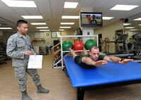 (From left) Airman 1st Class Carl Arguelles, 359th Medical Operations Squadron physical therapy technician, instructs Maj. Reuben Litton on the proper technique for the “superman”, a core work-out to strengthen core muscles. Members of the 359th Medical Operations Squadron ensure full spectrum clinical care from pediatric to adult patients for a population of more than 25,000 enrolled beneficiaries.  Members of the squadron also perform preventive health assessments, physical examinations, diagnostic services, treatment, disease management and immunization readiness.  (U.S. Air Force photo by Melissa Peterson/released)