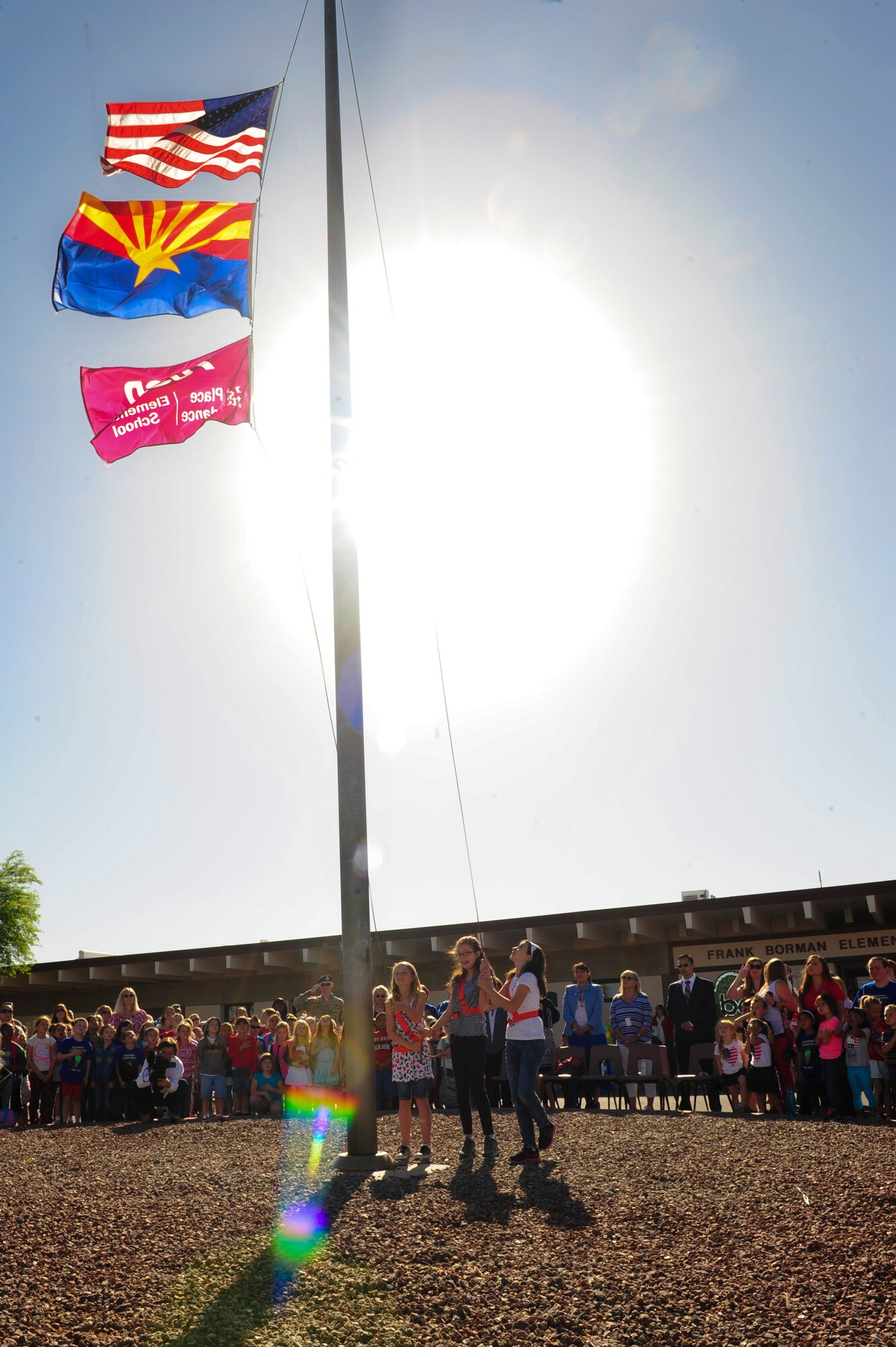 Elementary school students raise the American flag, Arizona flag and Tucson Unified School District flag at Borman Elementary School, Davis-Monthan Air Force Base, Ariz., April 10, 2015. The TUSD showed their support for April being the Month of the Military Child, by having the children of the TUSD wear red, white and blue on April 10. TUSD superintendent, along with other school officials attended the ceremony and thanked the children for their parents’ service. (U.S. Air Force photo by Airman 1st Class Cheyenne Morigeau/Released)