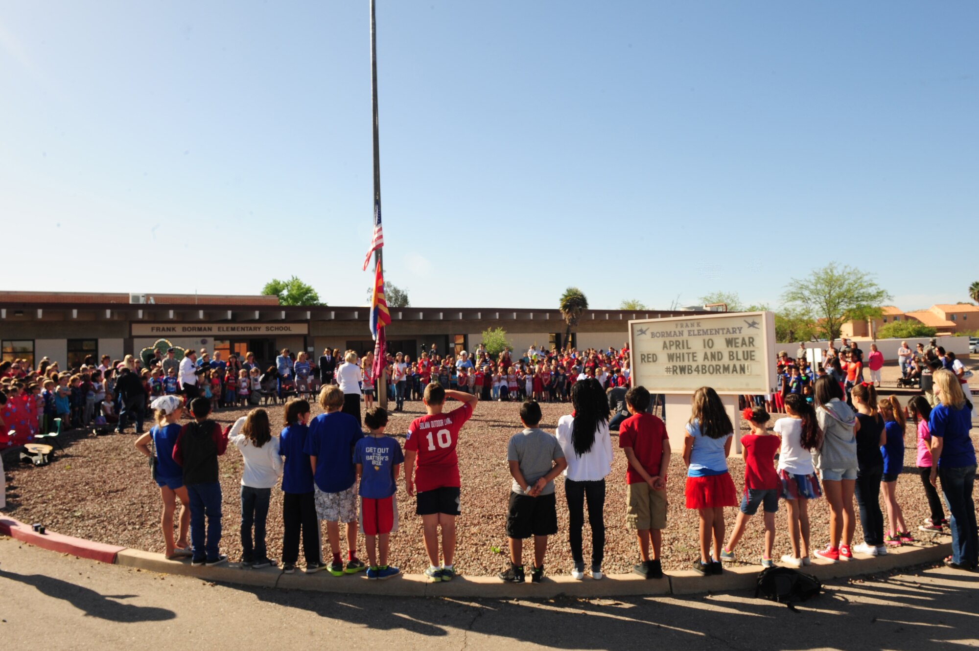 Students of Borman Elementary School gather together for a flag raising ceremony and wear red, white and blue clothing to honor the Month of the Military Child at Davis-Monthan Air Force Base, Ariz., April 10, 2015. During the ceremony, the children listened to guest speakers, recited the “Pledge of Allegiance” and sang additional patriotic songs. (U.S. Air Force photo by Airman 1st Class Cheyenne Morigeau/Released)  