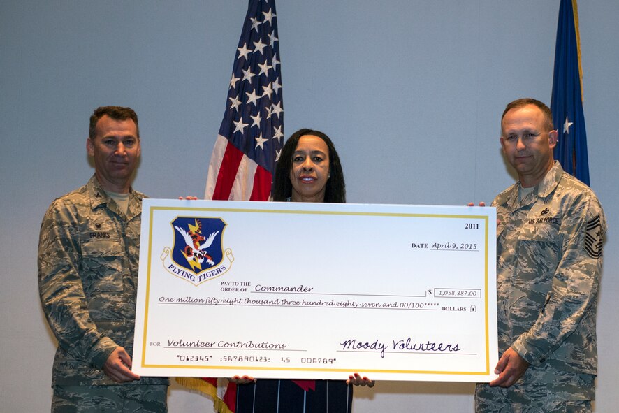U.S. Air Force Col. Chad Franks, 23d Wing commander, Camellia Jefferson, Moody Volunteer Program coordinator, and Chief Master Sgt. David Kelch, 23d WG command chief, pose for a photo with a large presentation check during the Volunteer Recognition Ceremony April 9, 2015, at Moody Air Force Base, Ga. Moody volunteers donated 48,109 hours of service in the community, which amounted to a $1,058,387 value. (U.S. Air Force photo by Airman Greg Nash/Released)