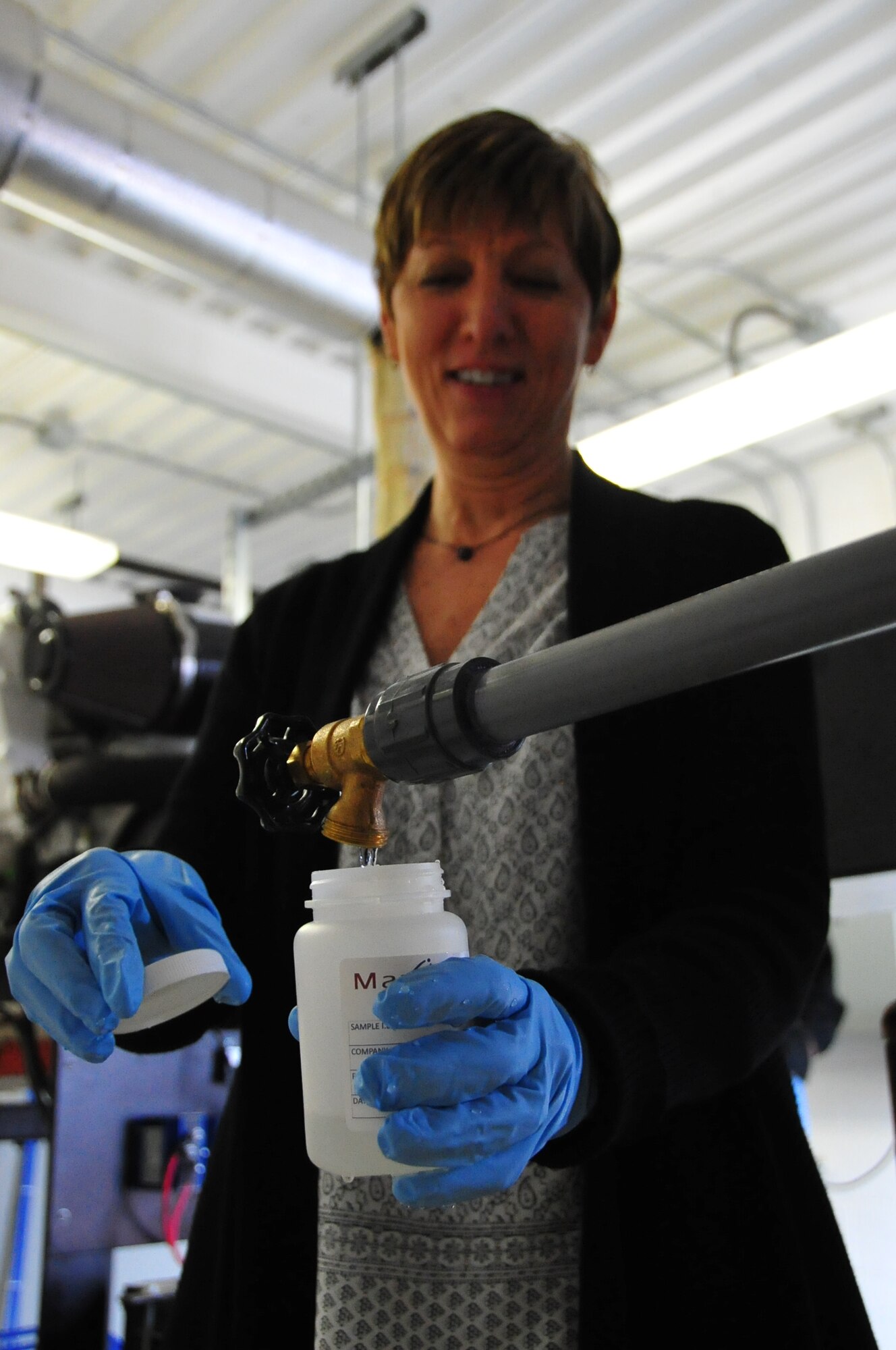 Kathy Lelevier, the 354th Medical Operations Squadron bioenvironmental drinking water program manager, collects a sample of water at Eielson Air Force Base, Alaska, April 7, 2015.  The sample is collected at the potable drinking water well, processed and shipped to a certified analysis lab. (U.S. Air Force photo by Tech Sgt. Miguel Lara III/Released)