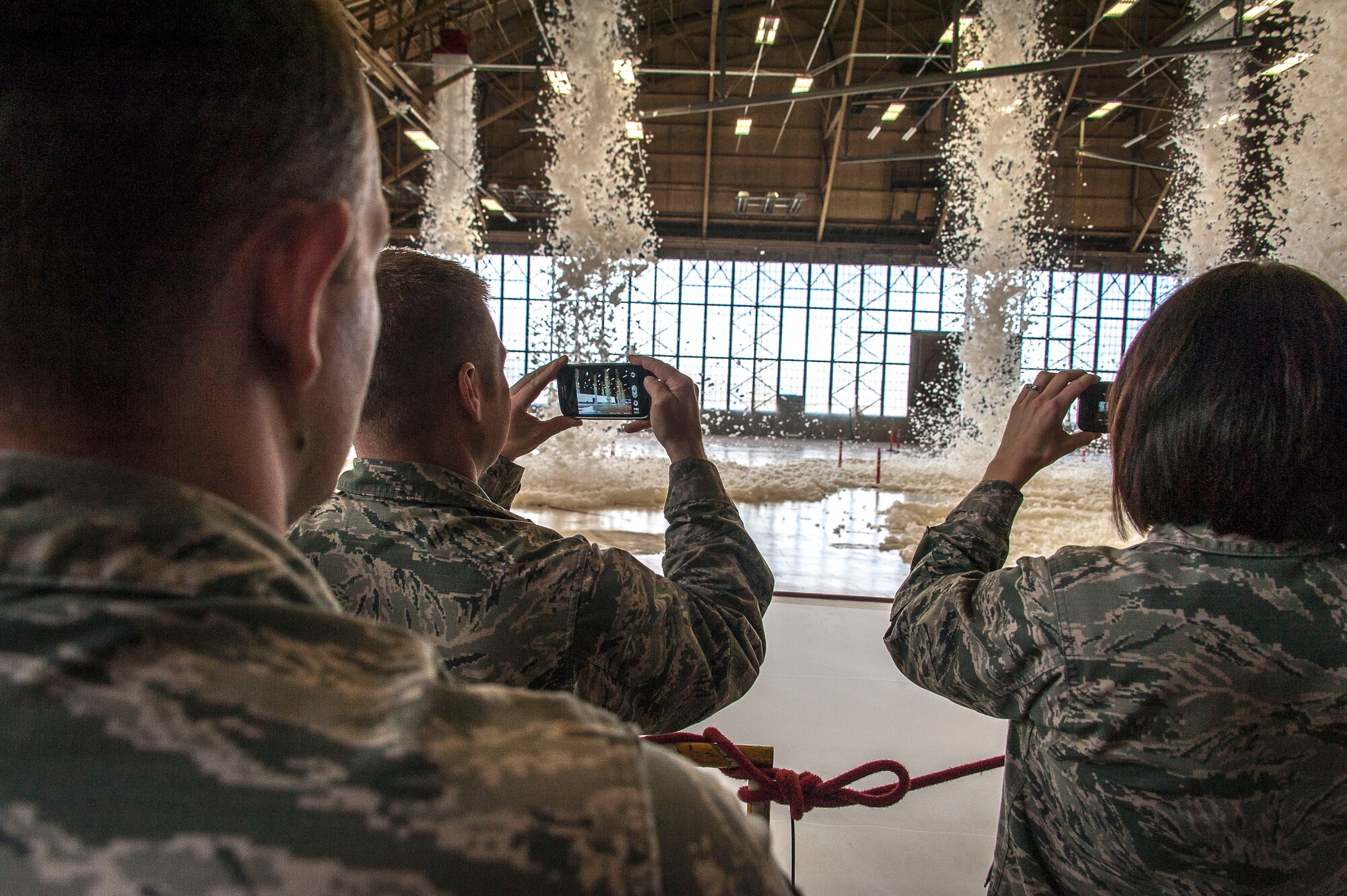 Airmen watch, record and gawk as fire suppression foam engulfs a maintenance hangar testing the installation’s high expansion foam discharge in the repair aircraft maintenance hangar April 8, 2015, at Fairchild Air Force Base, Wash. Tests like these are important as aircraft hangars, by their nature, pose unique challenges for the fire protection engineer. The hangar has large, open floor areas with tall roof decks to house Fairchild’s KC-135 Stratotanker. Large quantities of liquid jet fuel are present, and aircraft maintenance activities offer a variety of potential ignition sources. (U.S. Air Force photo/Staff Sgt. Benjamin W. Stratton)