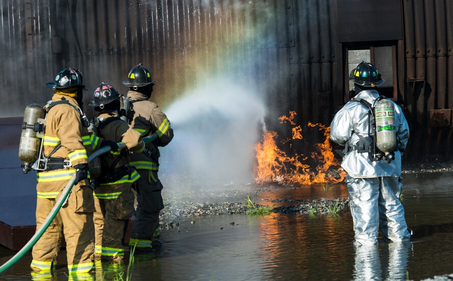 Firefighters from the 23d Civil Engineer Squadron and the Valdosta Fire Department, smother the flames with water during joint aircraft fire training April 8, 2015, at Moody Air Force Base, Ga. The training is held to ensure Airmen and local firefighters have adequate emergency response capabilities to respond and control live aircraft fires. (U.S. Air Force photo by Airman 1st Class Ceaira Tinsley/Released)