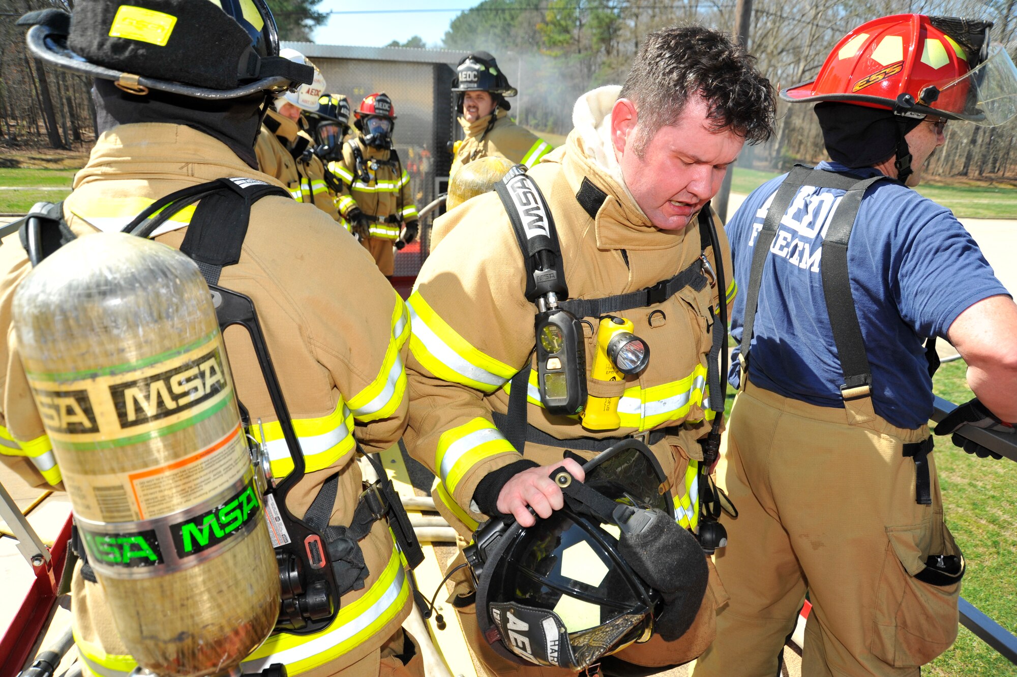 AEDC Paramedic/Firefighter Daniel Harris (center) exits the Kentucky Fire Commission mobile live fire rescue simulation training structure on March 23. Harris, along with 37 AEDC firefighters, participated in the annual training experiencing high temperatures and smoke, and practicing firefighting and self-rescue techniques. (Photo by Rick Goodfriend)