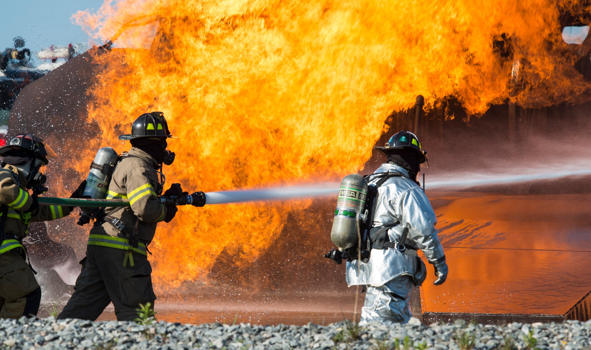 Firefighters from the 23d Civil Engineer Squadron and the Valdosta Fire Department, douse the flames before entering the simulated aircraft, during joint aircraft training April 8, 2015, at Moody Air Force Base, Ga. The VFD firefighters complete the required annual training to receive certification to support an aircraft fire at the local airport. (U.S. Air Force photo by Airman 1st Class Ceaira Tinsley/Released)