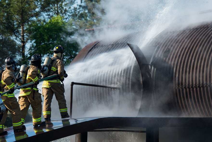 Firefighters from the Valdosta Fire Department, hose down the simulated aircraft before entering during joint aircraft training April 8, 2015, at Moody Air Force Base, Ga. The firefighters extinguished a fire for a simulated aircraft accident. (U.S. Air Force photo by Airman 1st Class Ceaira Tinsley/Released)
