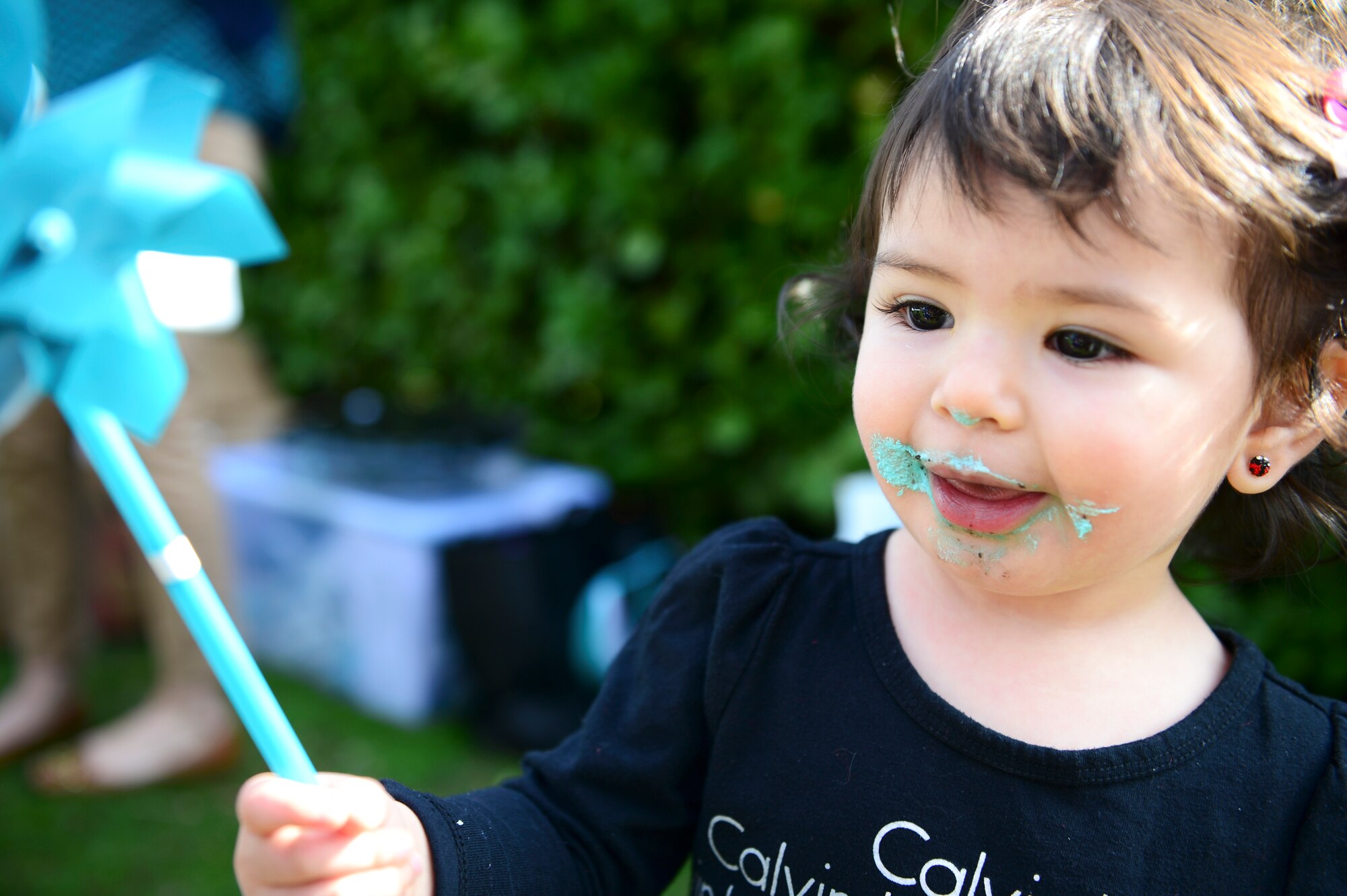 Alessandra Yepez, daughter of Carolina Yepez, 48th Fighter Wing Sexual Assault Response Coordinator, waves a teal pinwheel at the duck pond on Royal Air Force Lakenheath, England, April 10, 2015. The Sexual Assault Prevention and Response and Family Advocacy offices hosted Pinwheels in the Park to honor the survivors of sexual assault and child abuse. (U.S. Air Force photo by Airman 1st Class Dawn M. Weber/Released)
