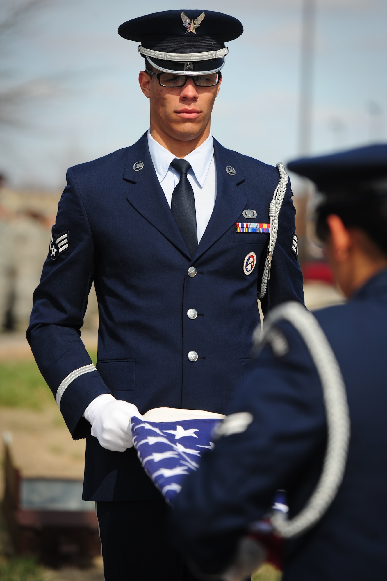 Senior Airman Eric Olivero and Airman 1st Class Desirae Yazzie, both from the Whiteman Air Force Base Honor Guard, brings down the flag during a retreat ceremony at Whiteman Air Force Base, Mo., March 27, 2015. A retreat ceremony signifies the end of a duty day and is also a way to pay tribute to the American flag. (U.S. Air Force photo by Staff Sgt. Nick Wilson/Released)