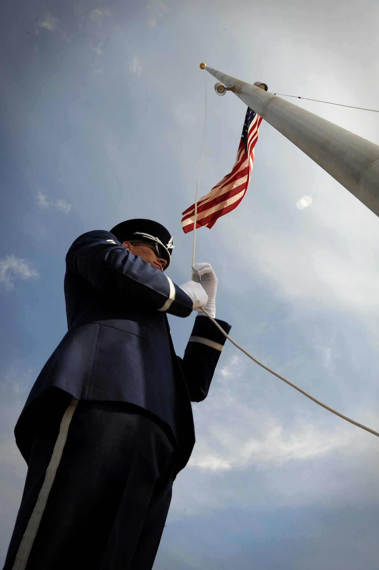 Senior Airman Eric Olivero, Whiteman Air Force Base Honor Guard member, lowers the flag during a retreat ceremony at Whiteman Air Force Base, Mo., March 27, 2015. A retreat ceremony signifies the end of a duty day and is also a way to pay tribute to the American flag. (U.S. Air Force photo by Staff Sgt. Nick Wilson/Released)