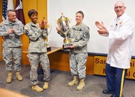 (From left) Col. Kevin Moore, chief, Department of Family and Community Medicine at Brooke Army Medical Center; Command Sgt. Maj. Tabitha Gavia, and BAMC Commander Col. Evan Renz present the Commander’s Award trophy to Col. Carol Rymer (holding trophy), BAMC’s optometry chief, during a ceremony March 17. The Optometry Service received the trophy to honor their stand-out dedication to safe, quality care during the first quarter of fiscal 2015. 
Photo by Robert Shields
