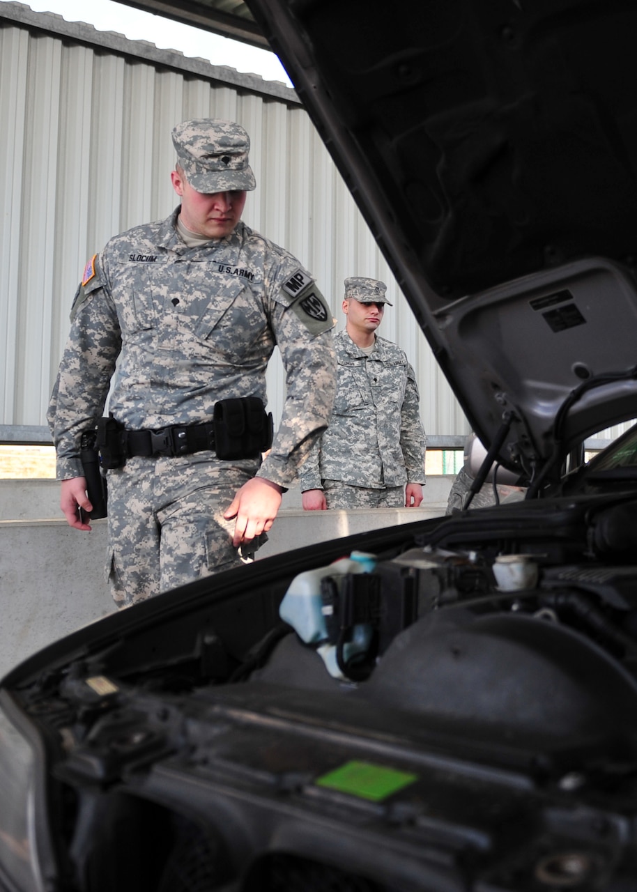 Army Spc. Brian Slocum, a military police soldier assigned to the 21st Theater Sustainment Command’s 92nd Military Police Company, 709th Military Police Battalion, 18th Military Police Brigade, inspects a vehicle during a patrol April 8 at Rhine Ordnance Barracks, Germany. U.S. Army photo by Sgt. 1st Class Alexander Burnett