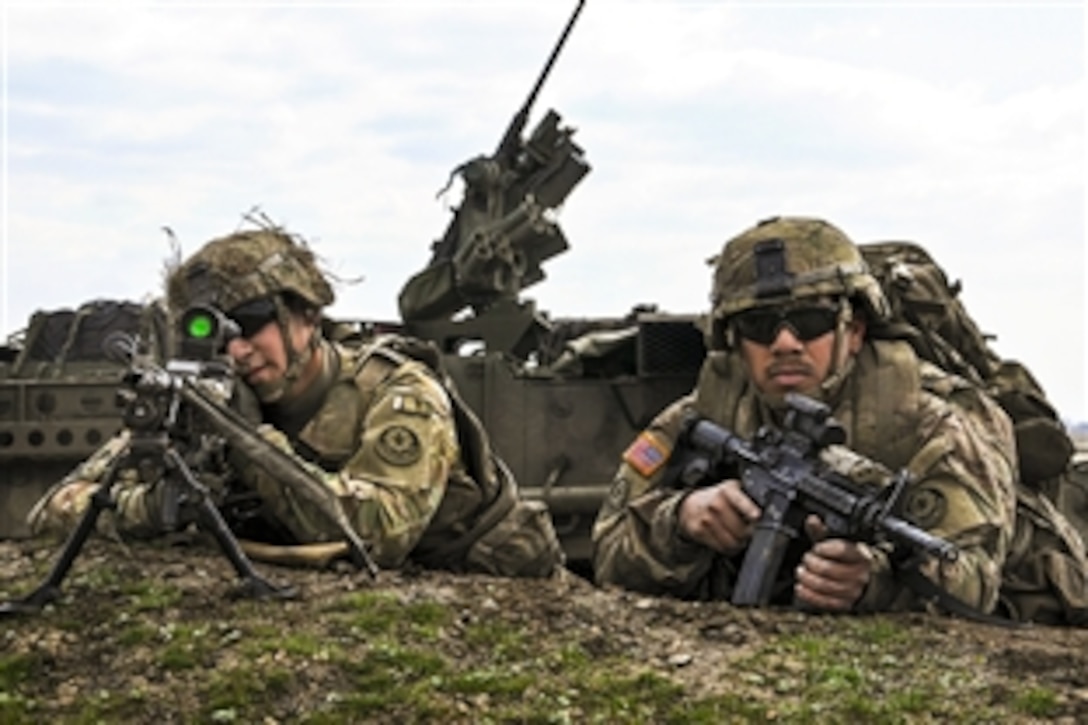 U.S. Army Pfc. Andrew Ochoa, left, and Army Spc. Nicholas Carrillo take a firing position during a live-fire exercise in Romania, April 8, 2015. Ochoa and Carrillo are assigned to the 2nd Cavalry Regiment. The exercise aims to demonstrate unit capabilities to Romanian military counterparts to support Operation Atlantic Resolve South. 