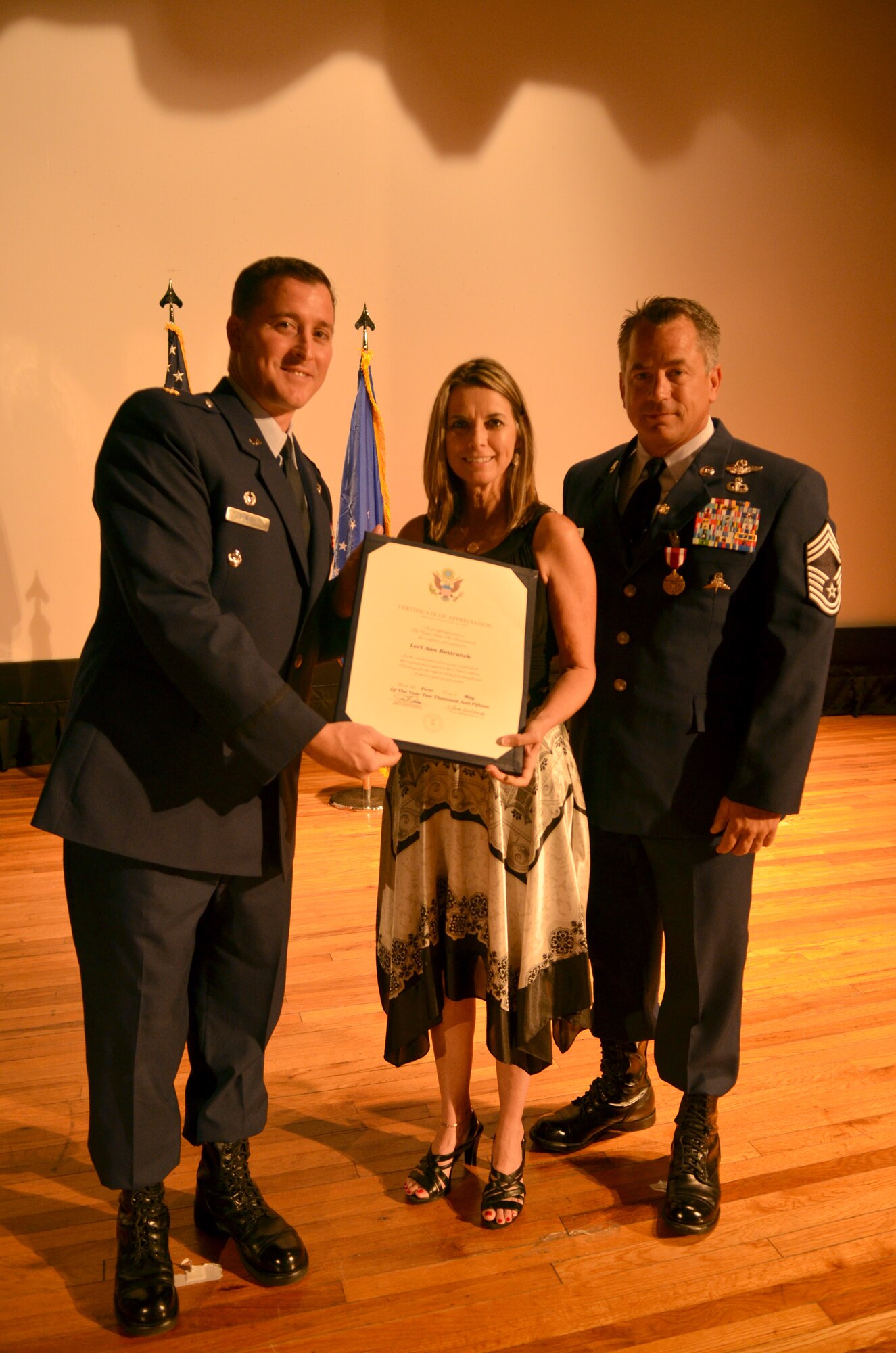 Maj. Chad Senior (left), commander, 308th Rescue Squadron, presents Lori Kestranek (middle) a certificate from the 920th Rescue Wing’s commander during Chief Master Sgt. Doug Kestranek’s (right) retirement ceremony. (U.S. Air Force photo/Senior Airman Natasha Dowridge)