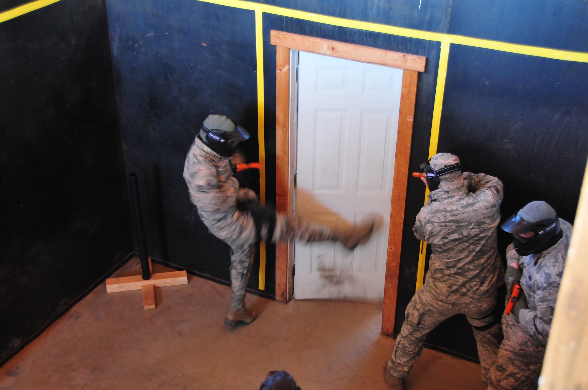 Staff Sgt. Michael Hayes breaches a door as Staff Sgt. Pablo Berchini and Staff Sgt. Nicholas Fay, members of the 161st Security Forces Squadron, prepare to clear a room inside a shoot-house during training, Phoenix, Jan. 16. Airmen practiced scenarios ranging from room clearing to entry procedures during a close quarters exercise as part of their annual training.