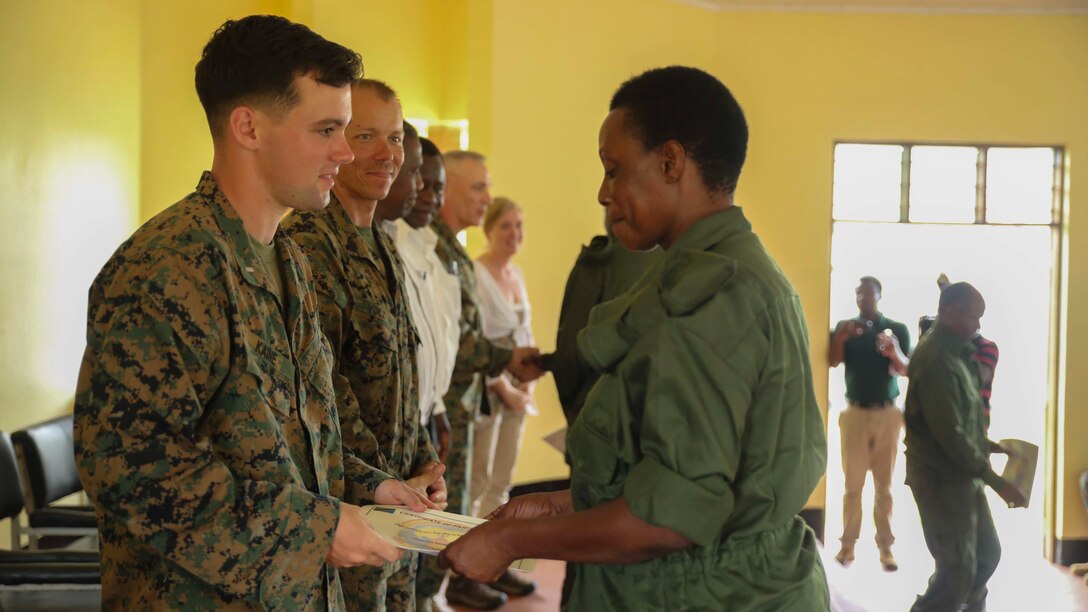U.S. Marine 1st Lt. Nathaniel Kaine, left, the Security Cooperation Team officer-in-charge with Special-Purpose Marine Air-Ground Task Force Crisis Response Africa, hands a Tanzanian park ranger a certificate of appreciation during a graduation ceremony on the Selous Game Reserve in Matambwe, Tanzania, March 27, 2015. More than 40 Tanzanian park rangers graduated from counter illicit-trafficking training. Approximately 15 Marines and Sailors taught the park rangers infantry skills to help combat illicit trafficking. 