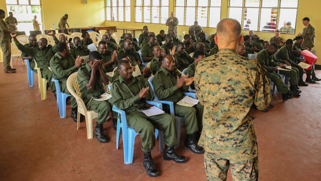 Marines and Sailors assigned to a Security Cooperation Team with Special-Purpose Marine Air-Ground Task Force Crisis Response-Africa and Tanzanian Park Rangers give themselves a round of applause after a graduation ceremony on the Selous Game Reserve in Matambwe, Tanzania, March 27, 2015. More than 40 park rangers graduated from a counter illicit-trafficking training, which was the first-ever engagement between U.S. Service members and Tanzanian park rangers. Approximately 15 Marines and Sailors taught the Park Rangers infantry skills to help combat illicit trafficking. 