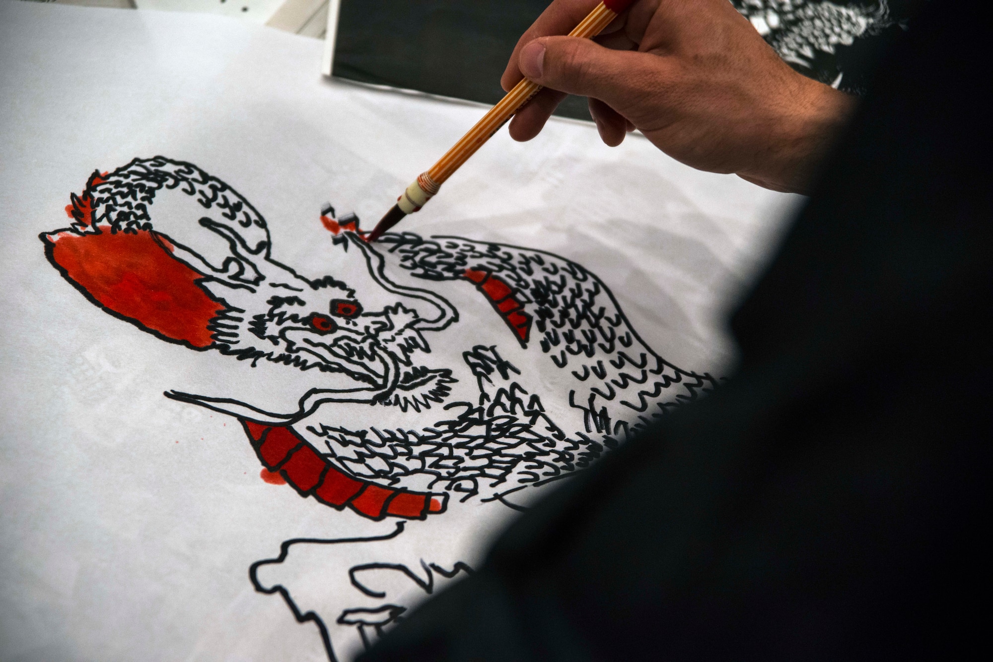 An Airman from Misawa Air Base, Japan, paints a dragon cartoon onto a kite April 11, 2015, during Japan Day. Dozens of Misawa residents worked with their Japanese counterparts creating art and constructing kites that were flown as part of the celebration of Japanese culture at Misawa.  (U.S. Air Force photo by Staff Sgt. Derek VanHorn/Released)