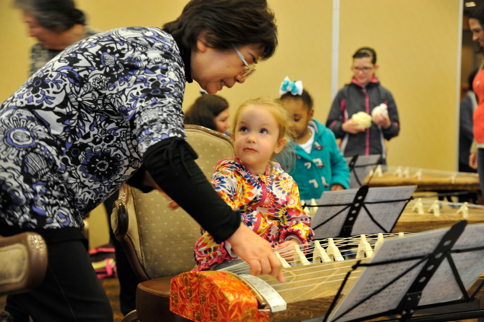 A Japan Day volunteer instructs a child how to play the koto, a traditional Japanese instrument, at Misawa Air Base, Japan, April 11, 2015. Volunteers from as close as Misawa City and even as far south as Iwate prefecture visited the base to share Japanese culture with Americans and their families. (U.S. Air Force photo by Senior Airman Patrick S. Ciccarone/Released)