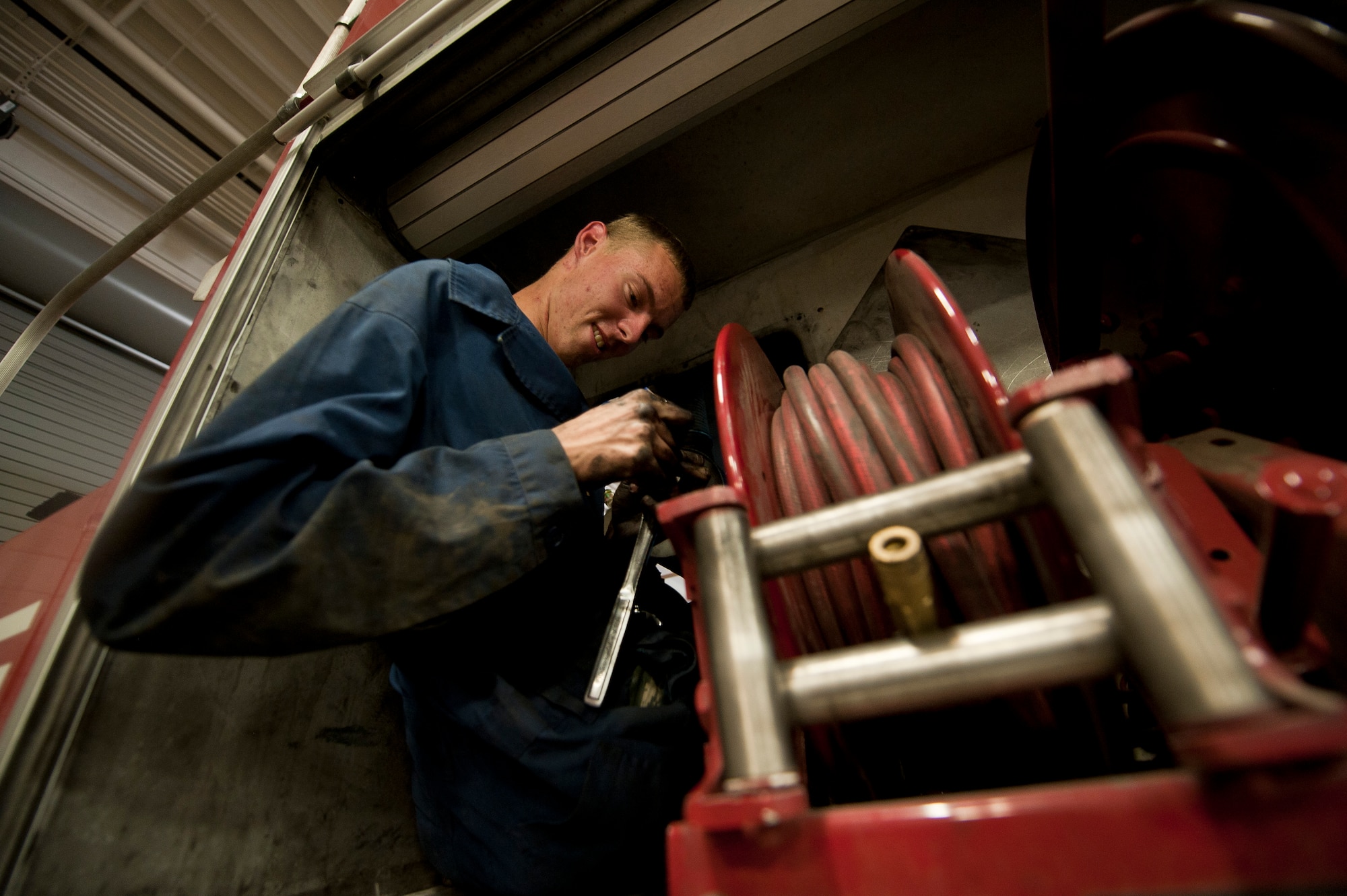 Airman 1st Class John Bordenkircher, 99th Logistics Readiness Squadron Vehicle Management Flight fire truck maintainer, prepares to disconnect a truck’s air compressor from its engine at Nellis Air Force Base, Nev., April 7, 2015. The fire truck Bordenkircher was working on was leaking anti-freeze into the engine, so Bordenkircher disconnected the air compressor to see if it was causing the leak. (U.S. Air Force photo by Staff. Sgt. Siuta B. Ika)