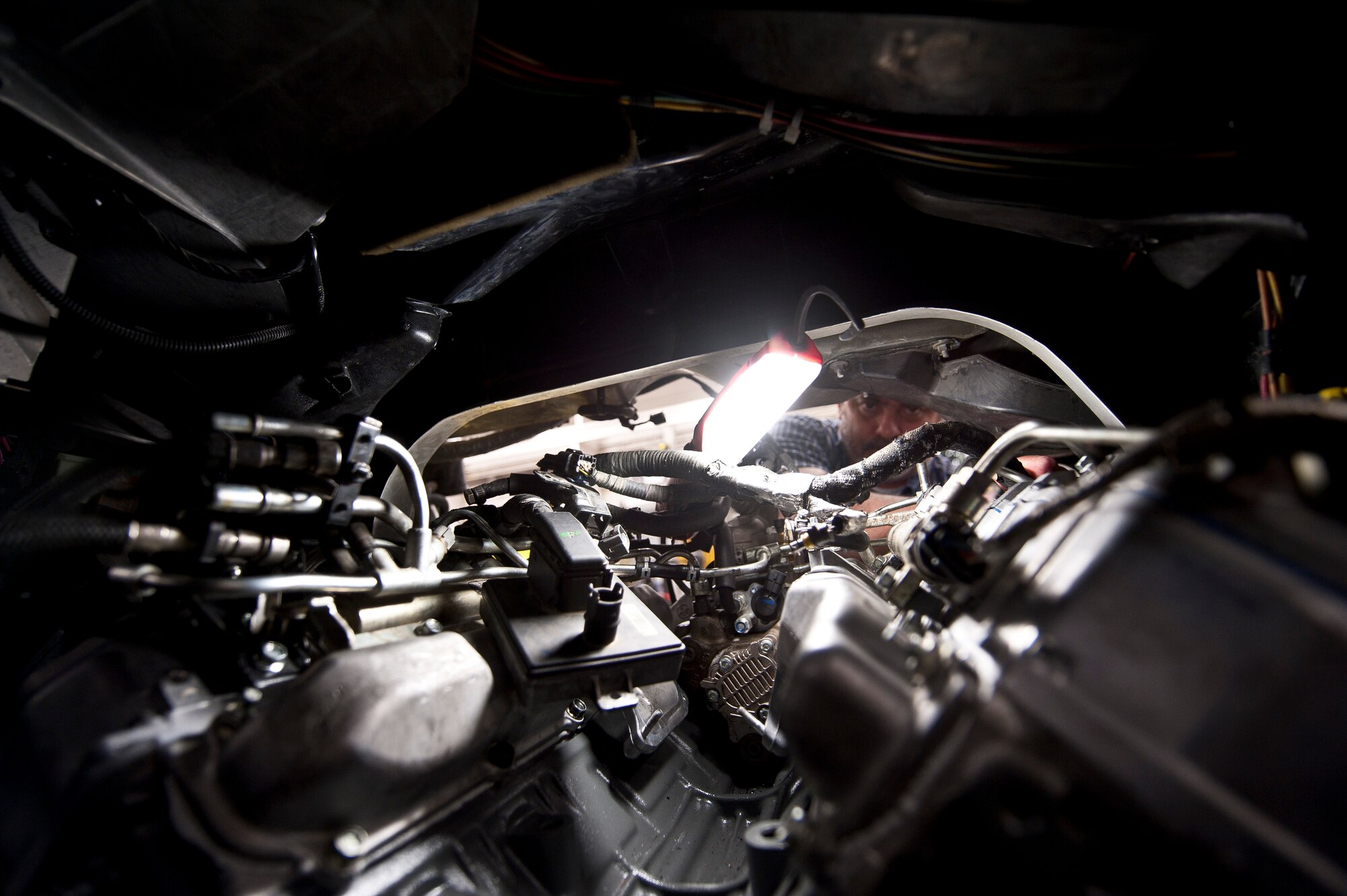 Bobby Padilla, 99th Logistics Readiness Squadron Vehicle Management Flight vehicle mechanic, puts a wiring harness on an engine component after replacing the engine at Nellis Air Force Base, Nev., April 7, 2015. Padilla, a retired technical sergeant, has worked as a mechanic at Nellis AFB for the last 12 years, including his last two years on active duty. (U.S. Air Force photo by Staff Sgt. Siuta B. Ika)