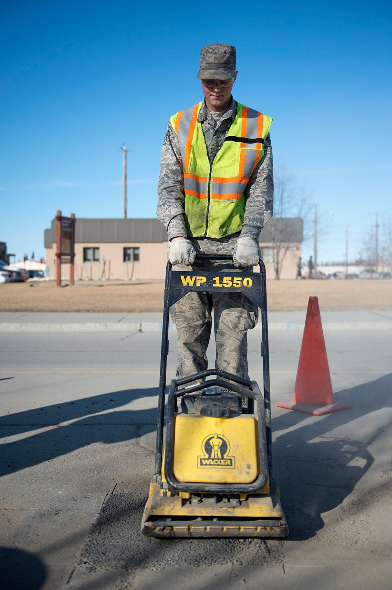 U.S. Air Force Airman 1st Class Jeremy Clapham, assigned to the 773rd Civil Engineer Squadron uses a plate compactor on newly applied asphalt while performing road improvements on Joint Base Elmendorf-Richardson, Alaska, April 3, 2015. The 773rd CES Airmen repaired potholes around base to maintain safe road conditions. (U.S. Air Force photo/Alejandro Pena)