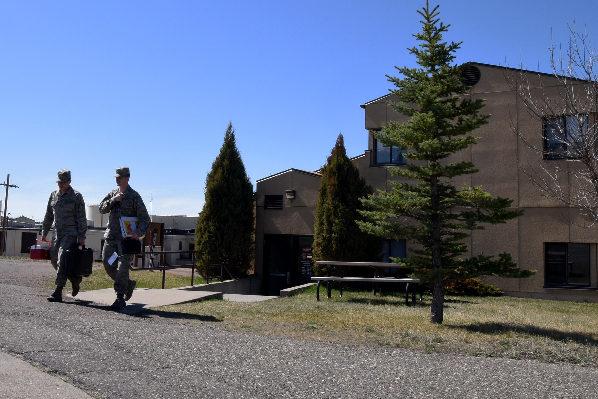 Airman 1st Class Joel Rogel, left, and William Raetz, 341st Medical Operations Squadron bioenvironmental engineering technicians, leave their building to perform a ventilation survey at the Auto Hobby shop April 8, 2015 at Malmstrom Air Force Base, Mont. Bioenvironmental routinely monitor 66 ventilation systems across the base to ensure safe working conditions. (U.S. Air Force photo/Chris Willis)