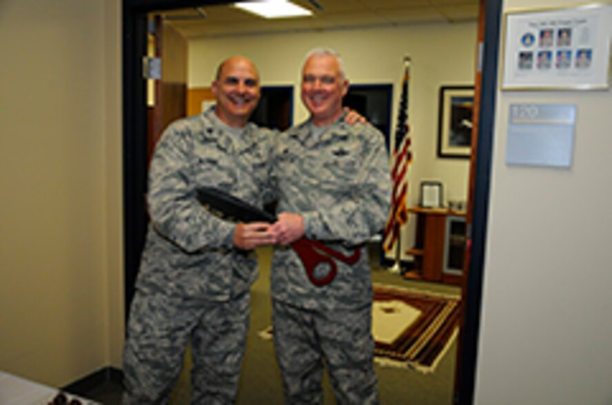 Chaplain (Lt. Col.) Pierre Allegre, 446th Airlift Wing chaplain (left) and Col. Scott McLaughlin, 446th AW commander, used extra-large scissors to cut the red ribbon at the grand opening of the new 446th AW chapel staff office. This new space features three offices that are sound proof for more privacy when talking with Reservists. Also, the office has a small area available for sermons and ceremonies as well as plenty of bibles, chocolates, and smiles up for grabs to any and all visitors. (U.S. Air Force Reserve photo by Senior Airman Madelyn McCullough)
