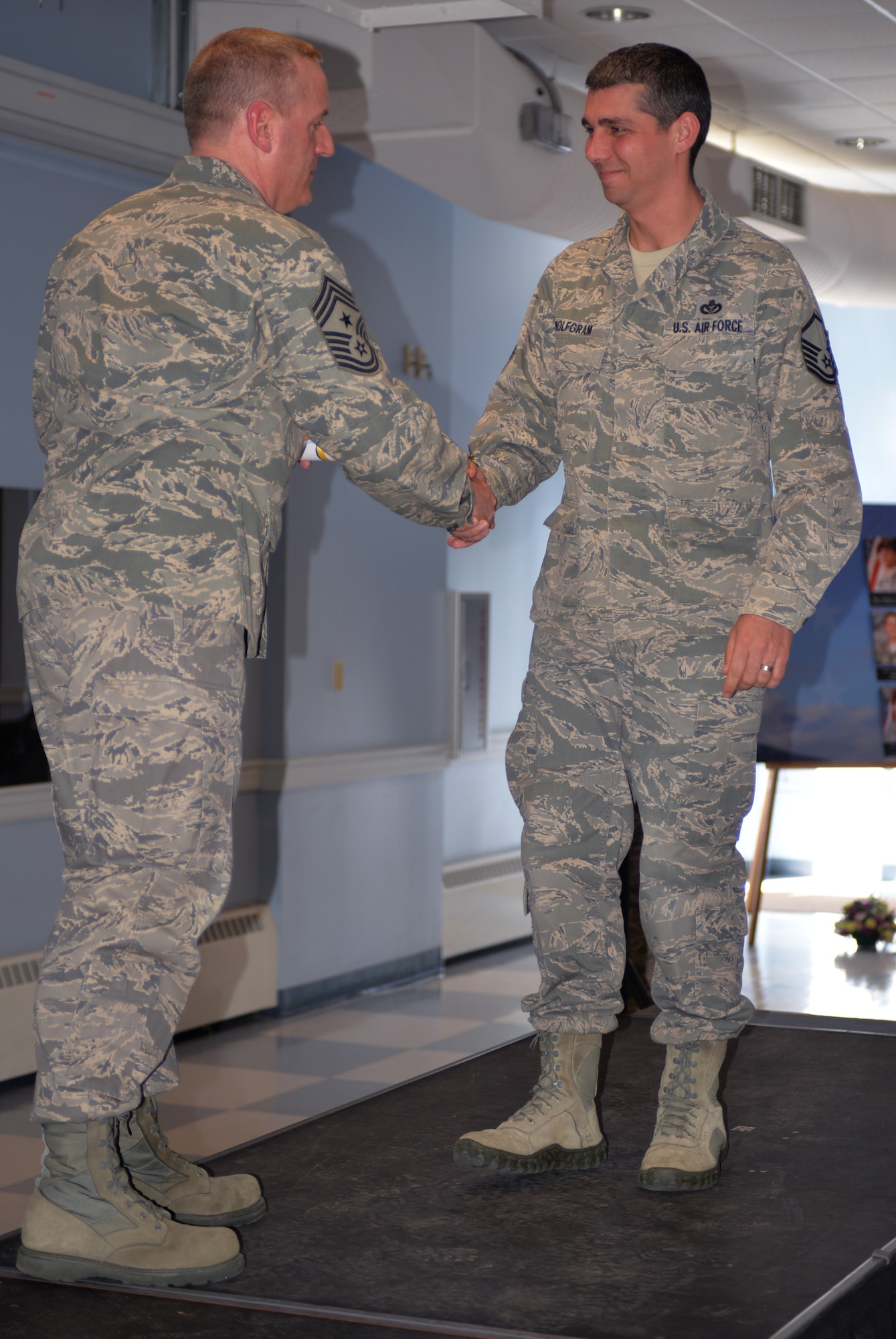 Master Sgt. Robert Wolfgram, a Community College of the Air Force, class of 2014 graduate, shakes hands with 157th Air Refueling Wing Command Chief Master Sgt. Jamie Lawrence during the Community Collage of the Air Force and Professional Military Education graduation ceremony April 12, 2015 at Pease Air National Guard Base. (N.H. Air National Guard photo by Airman Ashlyn J. Correia/RELEASED)