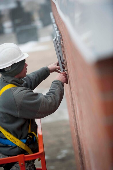 An Airman from the 5th Civil Engineer Squadron places letters on the base operations building on Minot Air Force Base, N.D., Jan. 27, 2015. Letters and shields were placed on the base operations building along with areas surrounding the front gate to welcome visitors and members of both the 5th Bomb Wing and 91st Missile Wing teams. (U.S. Air Force photos/Airman 1st Class Sahara L. Fales) 