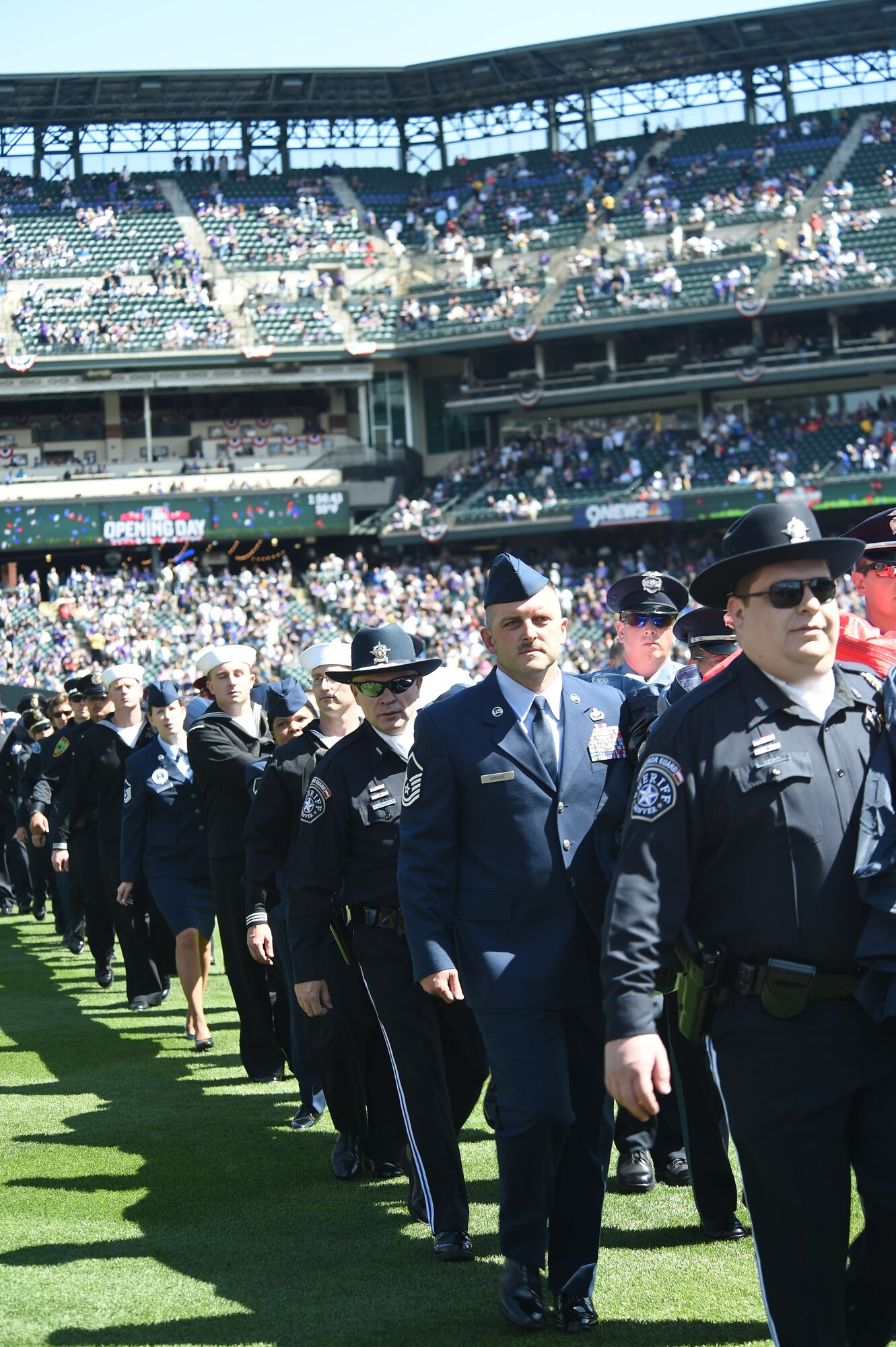 Service members and Colorado law enforcement carry the American flag off of the outfield during the Colorado Rockies Opening Day ceremony April 10, 2015, at Coors Field in Denver. Service members from all branches of service and Colorado law enforcement participated in the opening day festivities, to include an F-16 Fighting Falcon aircraft flyover and the unfurling of the American flag on the outfield. (U.S. Air Force photo by Airman 1st Class Samantha Saulsbury/Released)