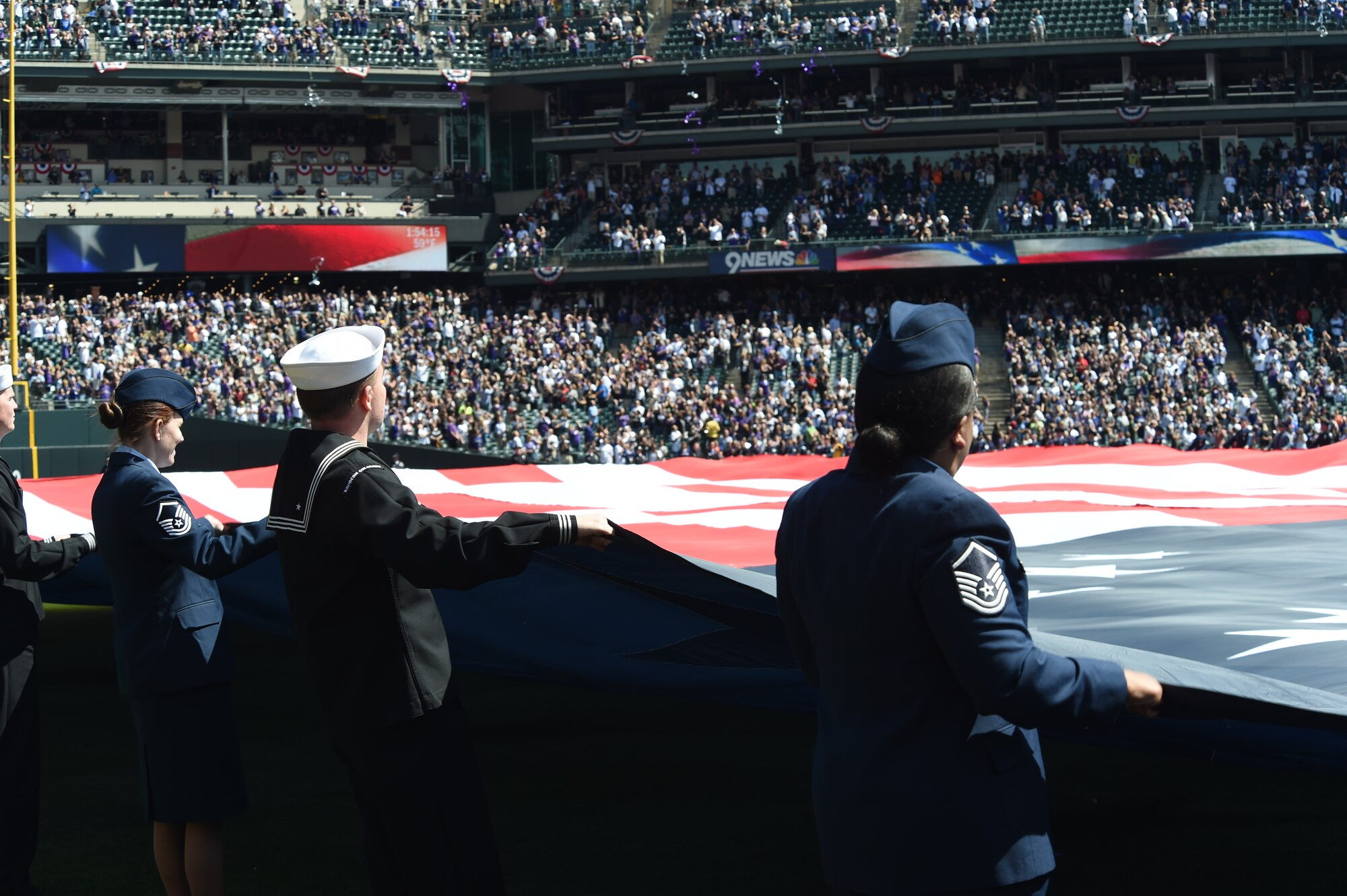 U.S. military members unfurl the American flag during the Colorado Rockies Opening Day ceremony April 10, 2015, at Coors Field in Denver. Service members from all branches of service and Colorado law enforcement participated in the opening day festivities. (U.S. Air Force photo by Airman 1st Class Samantha Saulsbury/Released) 