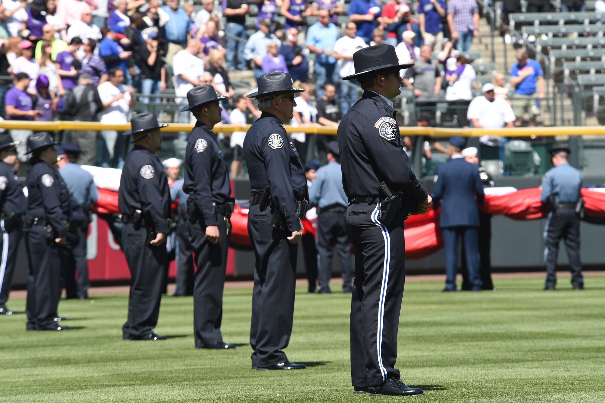 Colorado law enforcement officers and U.S. military members wait to unfurl the American flag on the outfield April 10, 2015, at Coors Field in Denver. Service members from all branches of service and Colorado law enforcement participated in the opening day festivities. (U.S. Air Force photo by Airman 1st Class Samantha Saulsbury/Released)