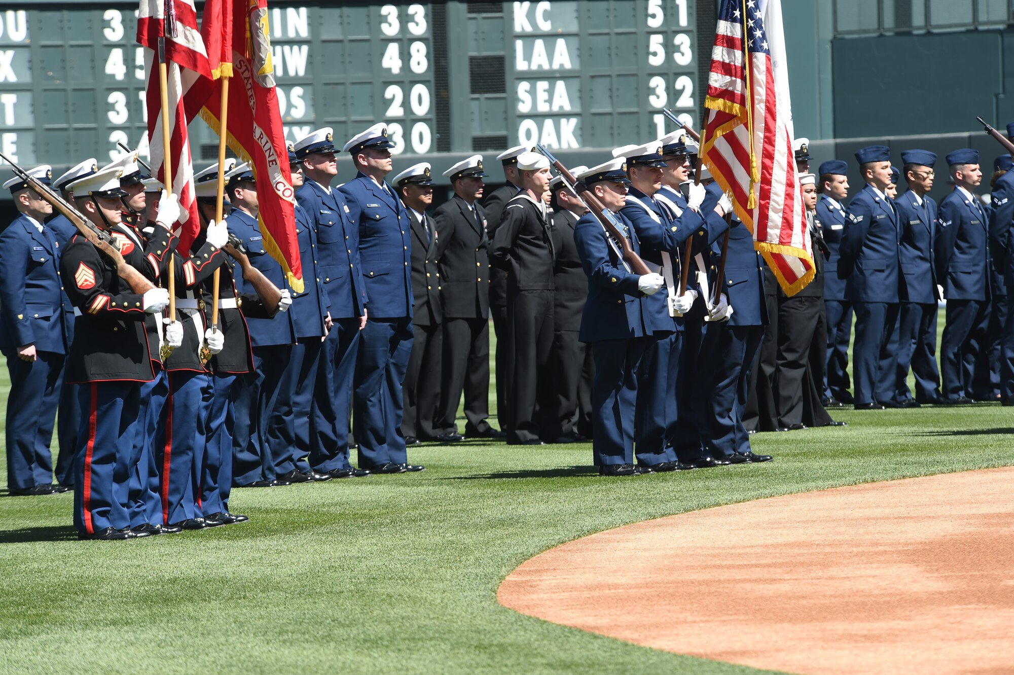 Service members from all U.S. military branches stand in formation during the Colorado Rockies Opening Day ceremony April 10, 2015, at Coors Field in Denver. Service members from all branches of service and Colorado law enforcement participated in the opening day festivities, to include an F-16 Fighting Falcon aircraft flyover and the unfurling of the American flag on the outfield. (U.S. Air Force photo by Airman 1st Class Samantha Saulsbury/Released) 