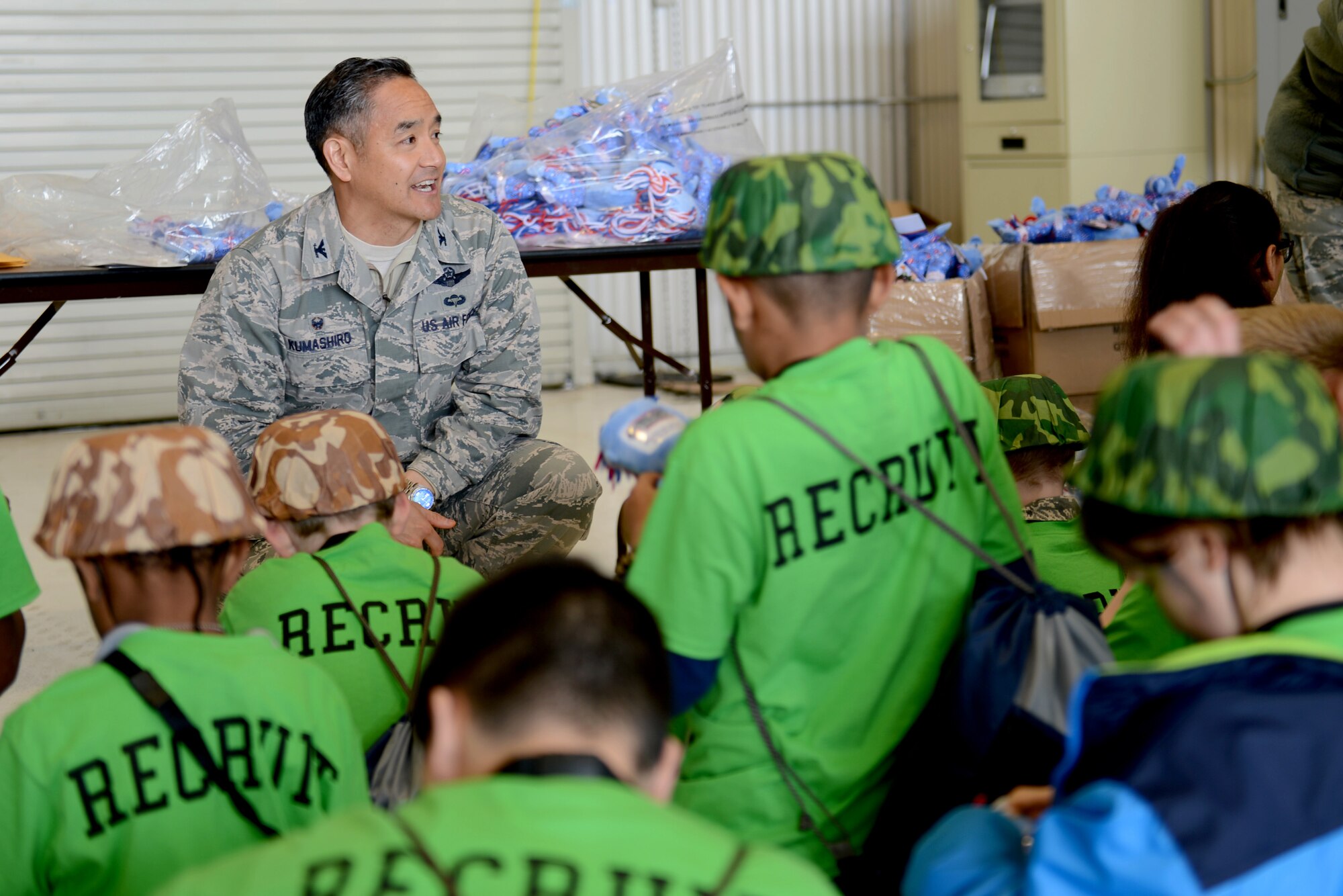 Col. David Kumashiro, 62nd Airlift Wing commander, talks to the children about their parent’s deployment process April 11, 2015, during the Kids Understanding Deployment Operations event at Joint Base Lewis-McChord, Wash. During KUDOs, the children played games such as a team run to simulate a bag drag, and received dolls that represented their Wingmen. (U.S. Air Force photo/Airman 1st Class Keoni Chavarria)