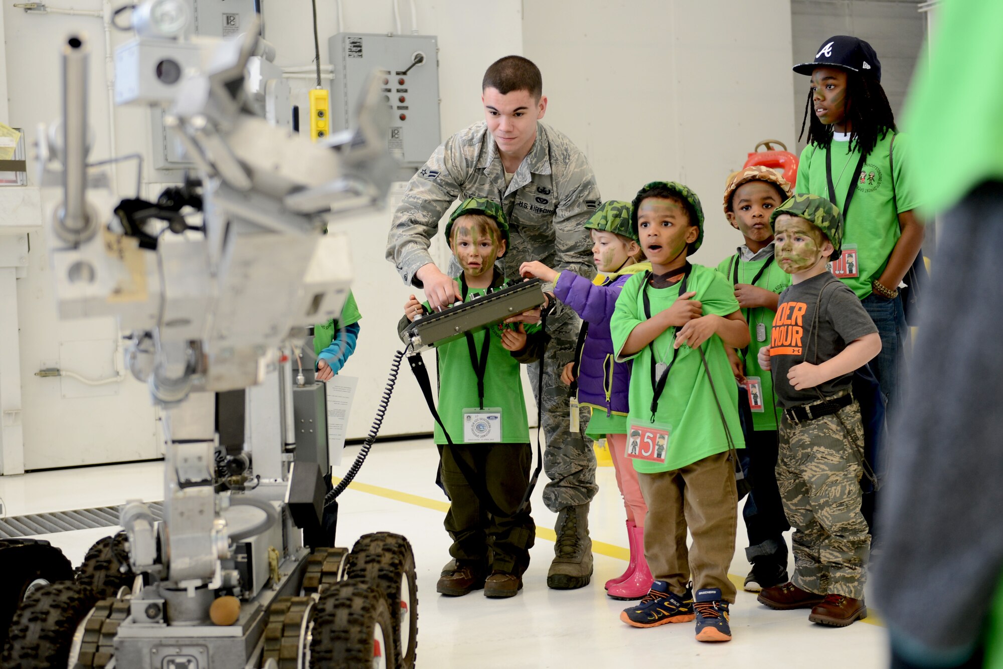 Airman 1st Class Jeremiah Alejandro, 627th Civil Engineer Squadron explosive ordinance disposal journeyman, shows children how a remote controlled machine works, April 11, 2015, during the Kids Understanding Deployment Operations event at Joint Base Lewis-McChord, Wash. KUDOs was an exercise to help give children a better understanding of how a deployment process works. (U.S. Air Force photo/Airman 1st Class Keoni Chavarria)