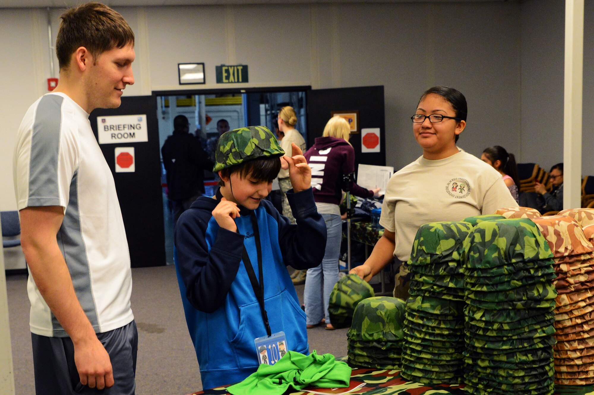 Staff Sgt. Andrew Snow (left), 62nd Maintenance Squadron aerospace ground equipment technician, and his son walk through the deployment processing line, April 11, 2015, during the Kids Understanding Deployment Operations event at Joint Base Lewis-McChord, Wash. KUDO is a version of a deployment processing line that included stations for children to pick up dog tags, t-shirts, and helmets. (U.S. Air Force Photo/Senior Airman Rebecca Blossom)
