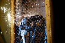 Senior Airman Jesus Contreras, 91st Security Forces Group tactical response force member uses an electric saw to cut through a fence during training on Minot Air Force Base, N.D., April 8, 2015. TRF is a nuclear special weapons and tactics team specializing in recapture and recovery operations. (U.S. Air Force photo/Senior Airman Brittany Y. Bateman)