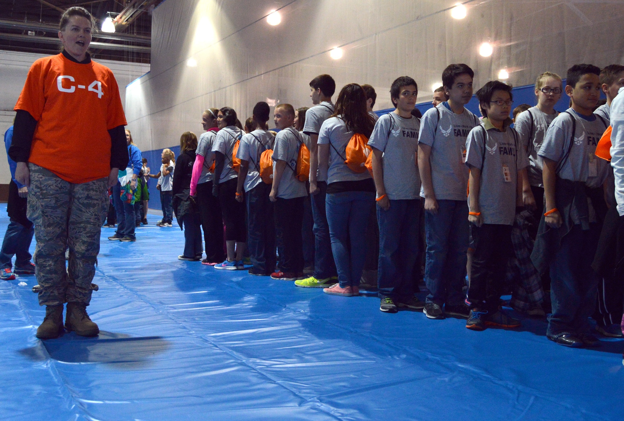 U.S. Air Force Staff Sgt. Janet Poit, 557th Weather Wing knowledge operator, teaches fifth and sixth graders how to stand at attention April 9 in the Offutt Field House during the Junior Pre-Deployment Function program. More than 250 students from local schools and homeschoolers attended the event where they experienced a simulated deployment. (U.S. Air Force photo by Staff Sgt. Dallas Edwards)