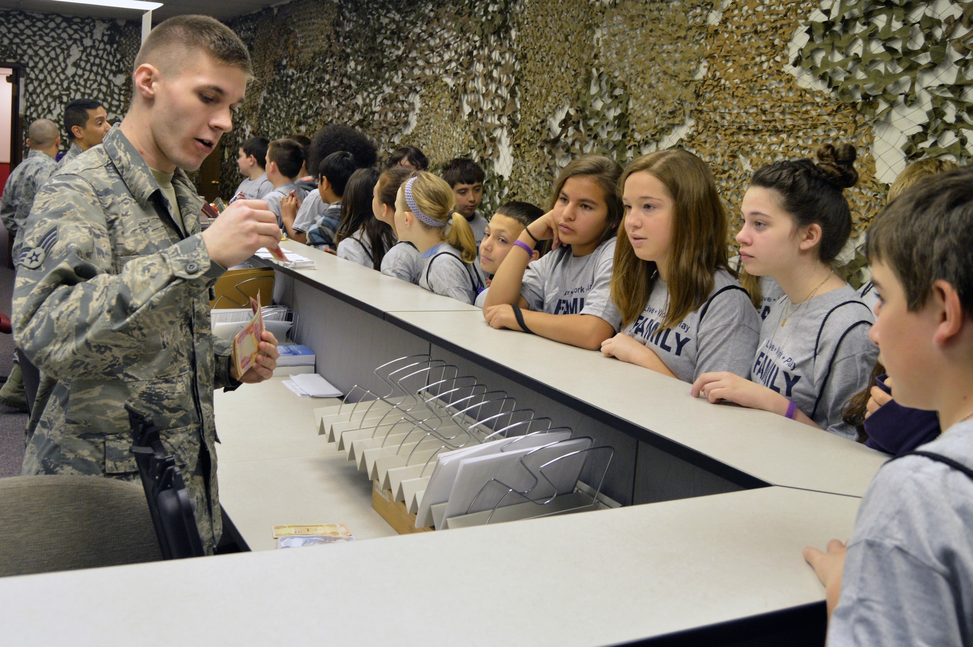U.S. Air Force Senior Airman Daniel Anderson, 55th Comptroller Squadron, shows local fifth and sixth graders Iraqi currency April 9 during the Junior Pre-Deployment Function program at Offutt Air Force Base, Nebraska. The students went through a series of events to include the pre-deployment processing line where they heard from organizations like medical, finance and the chapel. (U.S. Air Force photo by Staff Sgt. Dallas Edwards)
