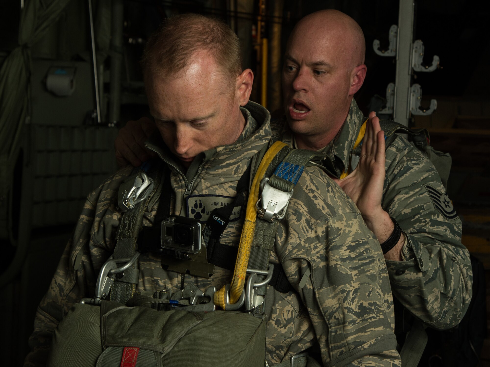 Tech. Sgt. Brian Angell, 435th Contingency Response Group personal parachute program manager, checks Master Sgt. James Burke's, 435th Contingency Response Group airfield manager, parachute April 8, 2015 at Powidz Air Base, Poland. While deployed to Poland for training, Burke re-enlisted into the Air Force on a C-130J Super Hercules before parachuting out. (U.S. Air Force photo/Senior Airman Jonathan Stefanko)
