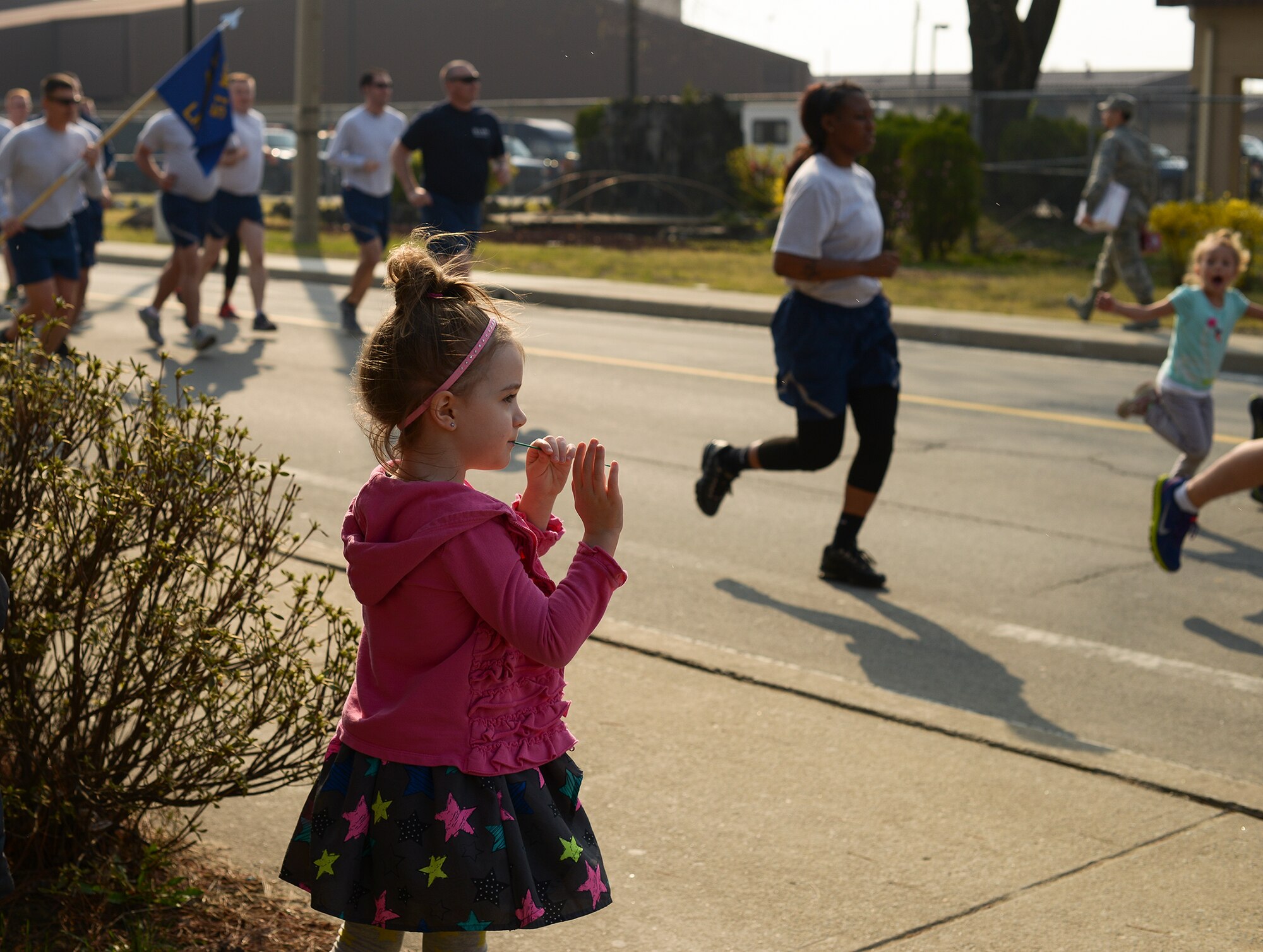 Lilia Trickey, daughter of Michaela and Senior Master Sgt. Jason Trickey, cheers on her father and other run participants during the Team Osan resiliency run April 10, 2015, at Osan Air Base, Republic of Korea. The run was open to the entirety of Team Osan, and marked the beginning of the 51 days of resiliency. (U.S. Air Force photo by Staff Sgt. Jake Barreiro/Released)